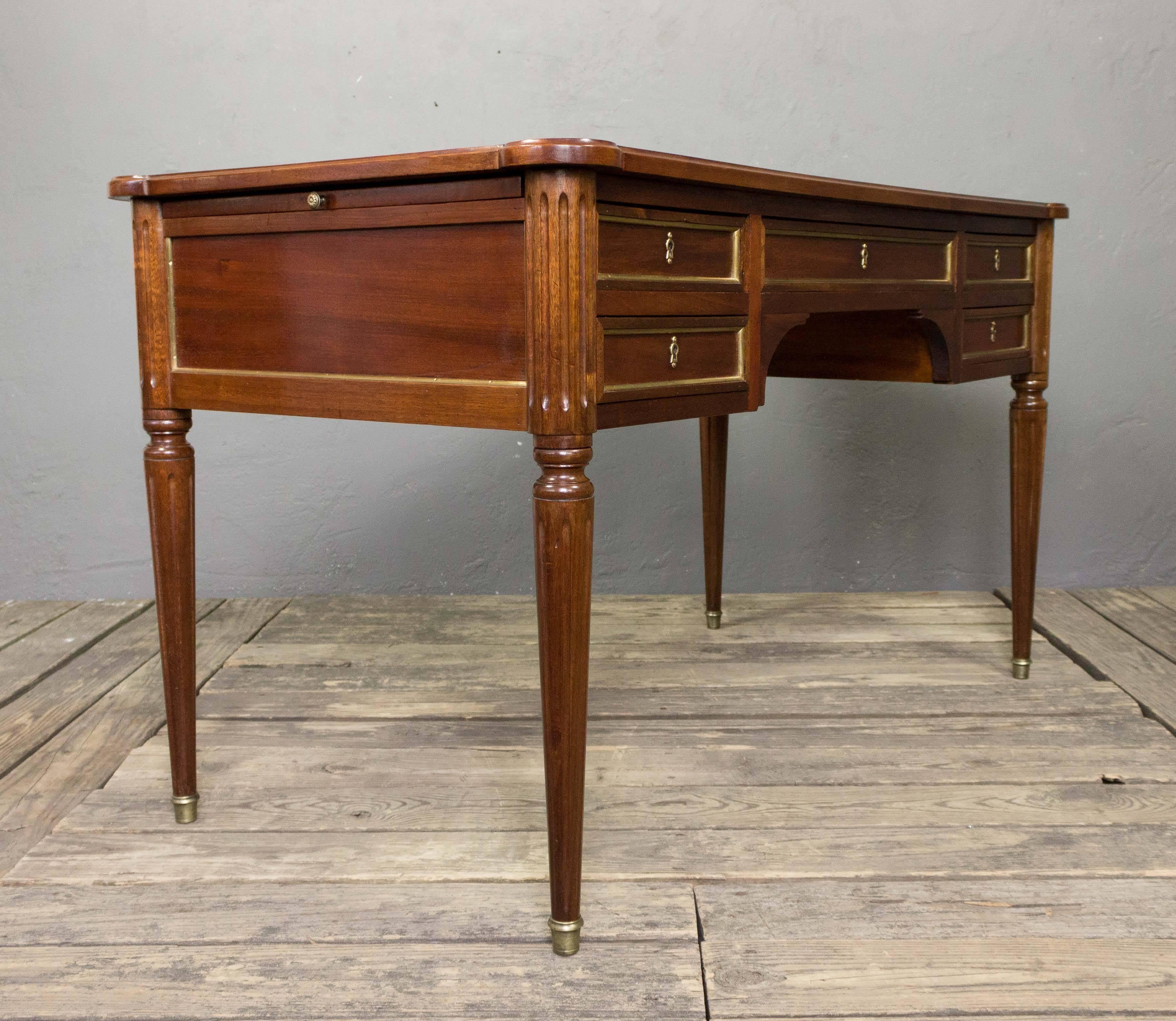 Handsome mahogany desk with leather top. The desk has five drawers and two pull-out tablets on either side. The back is finished so the deck can be seen from the backside.  Recently polished. France, Early 20th Century

