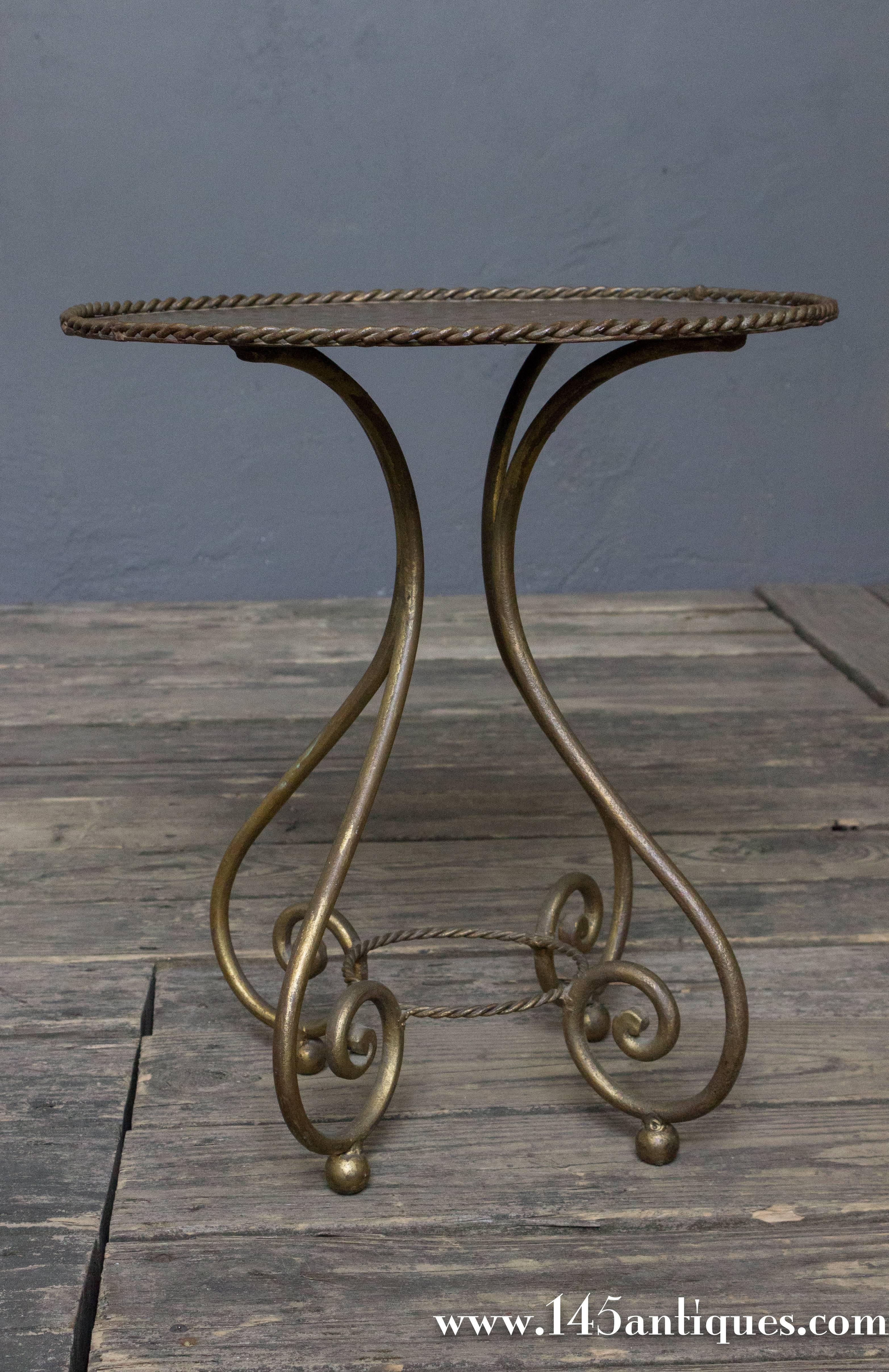 Spanish round gilt martini table with four scrolled legs and hammered top with braiding detail.