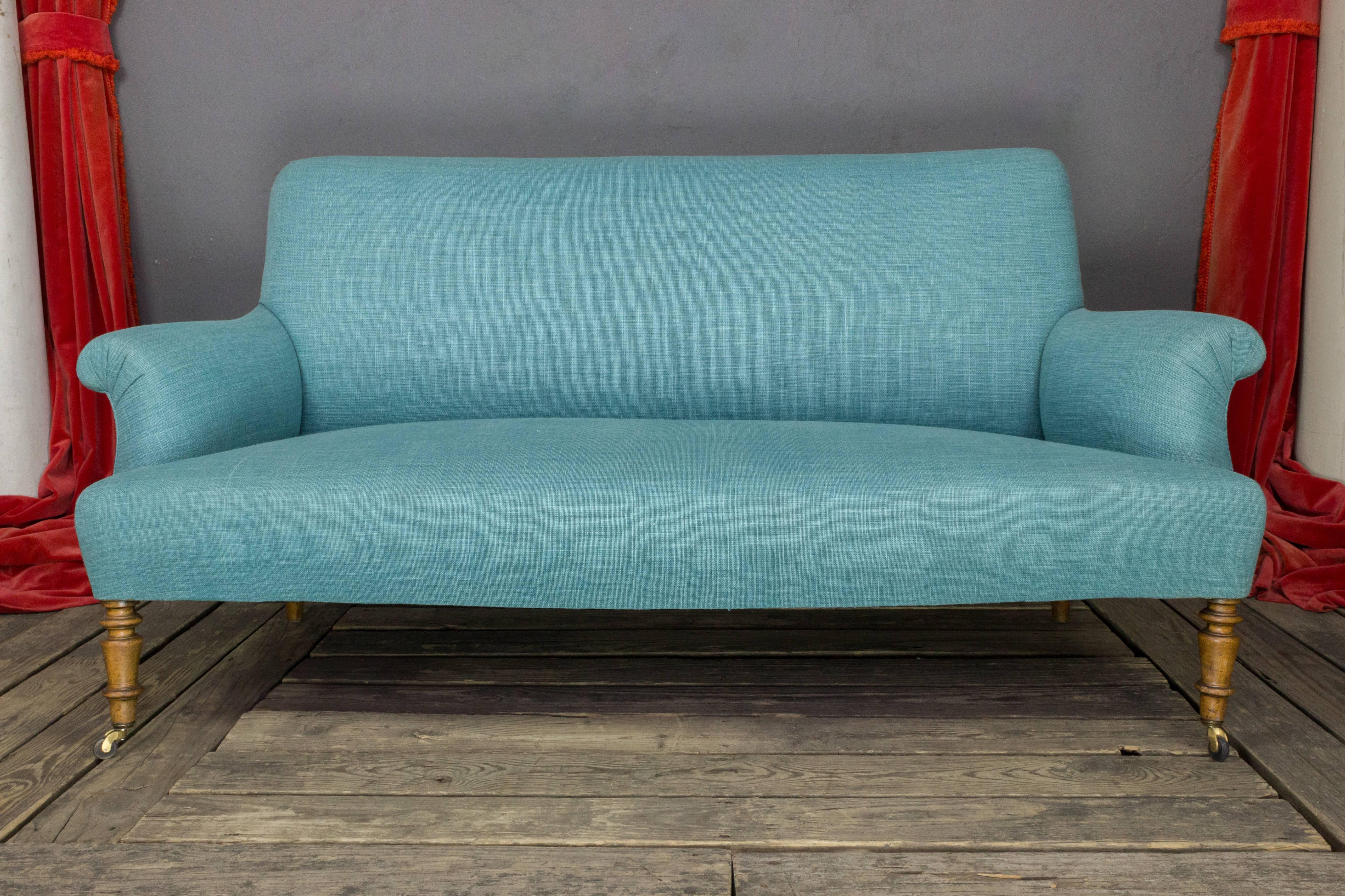 19th century French settee recently upholstered with fresh lagoon colored linen and castors added to front legs.