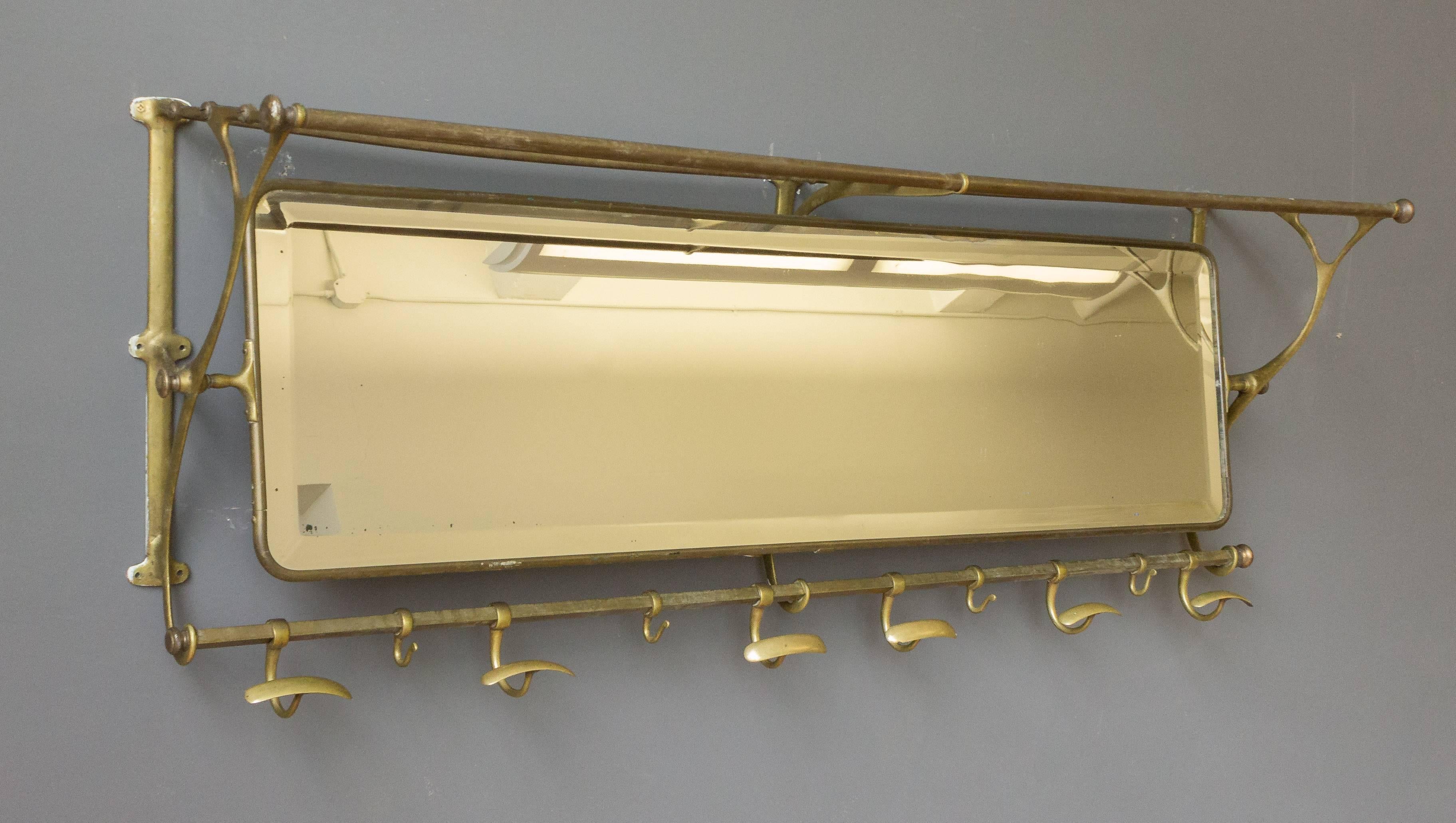 Brass coat rack with bevelled mirror and alternating hat and smaller coat hooks, French, 1920s. Original vintage condition, shows signs of age and use.


         