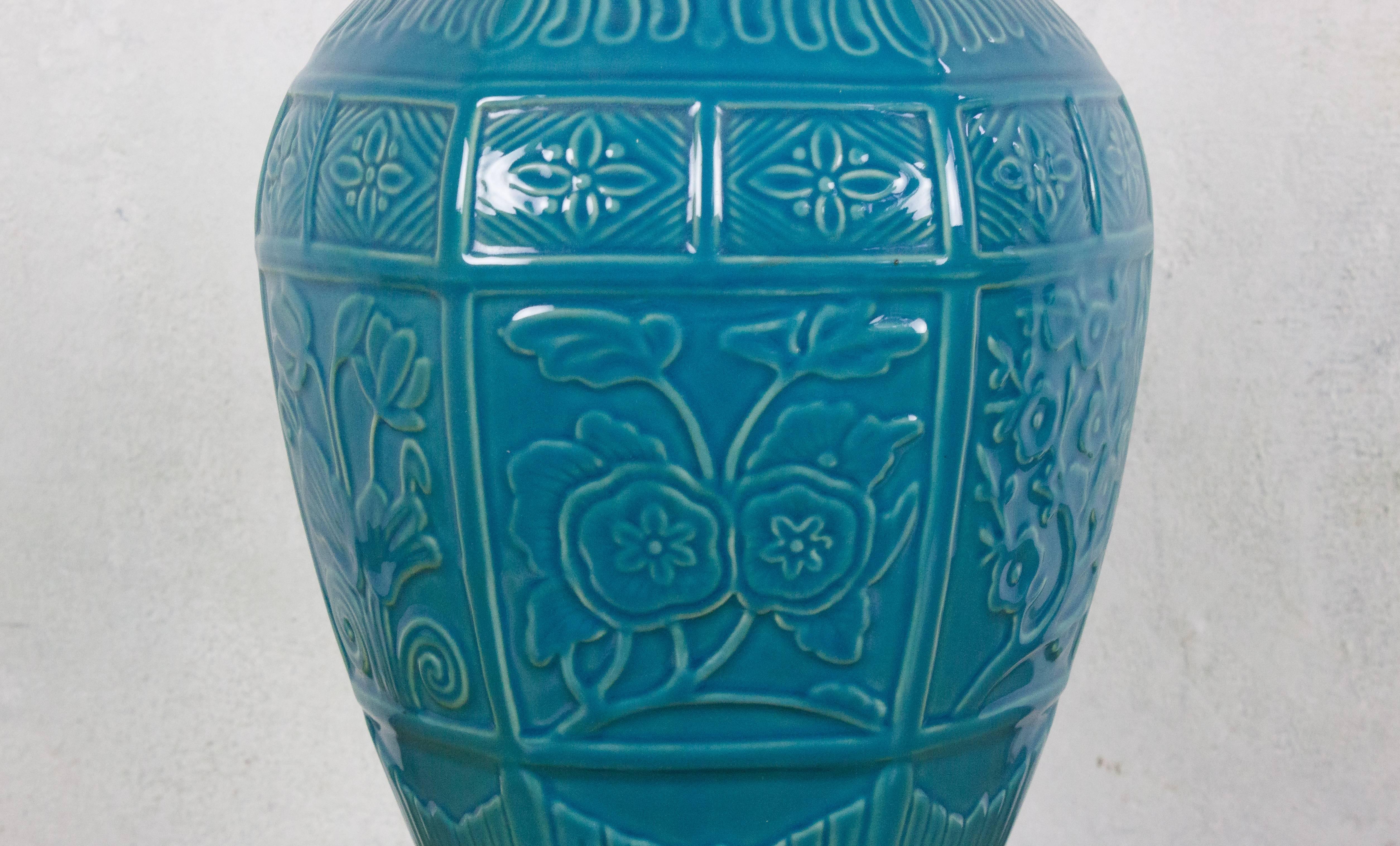 This French 1940s turquoise ceramic lamp features an Asian-inspired motif, adding a touch of cultural charm to any space. Mounted on a pentagonal stepped ebonized wooden base, the lamp stands at an impressive height of 34 inches with a sturdy 7-inch
