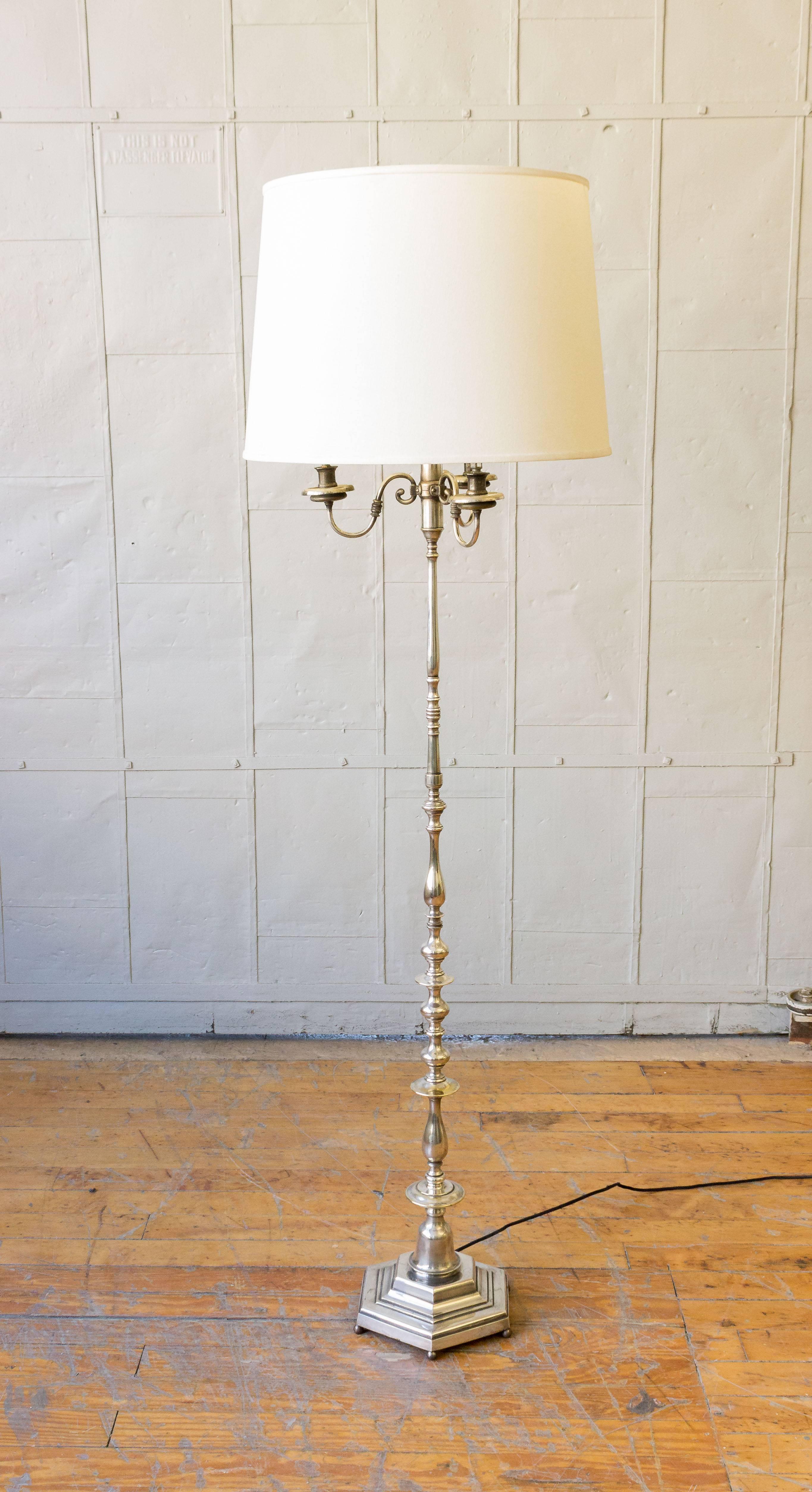 This French floor lamp from the 1940s is a remarkable vintage piece that features a silver plated brass construction. Resting on a hexagonal base, this lamp adds a touch of elegance to any room. While there may be some tarnishing and wear on the