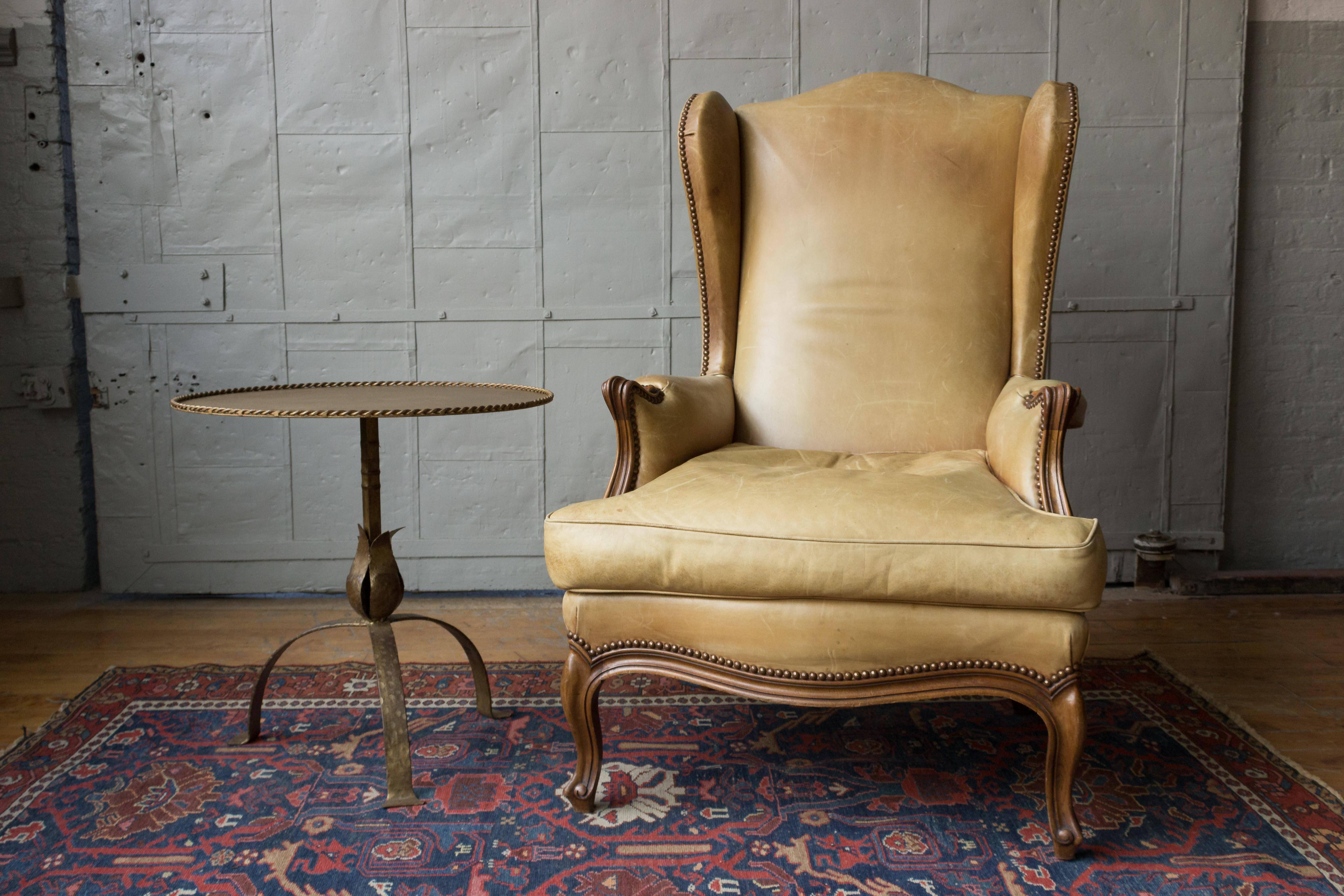 A gilt iron side table mounted on a tripod base. The metal has a rich dark gilt patina showing some hammered texture detail. The top is enclosed in a twisted roping gallery, Spanish, 1950s.