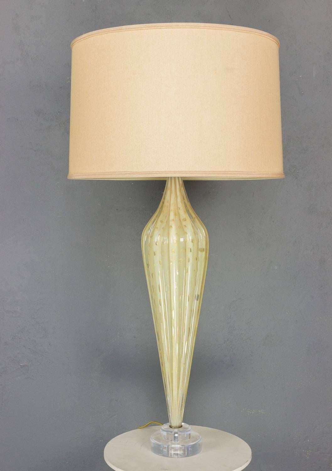 This is a rare and stunning handblown Murano lamp from the 1940s, crafted by skilled artisans in Italy. The lamp features ribbed glass in a beautiful golden yellow hue with intricate gold inclusions that add depth and texture. Recently rewired, this