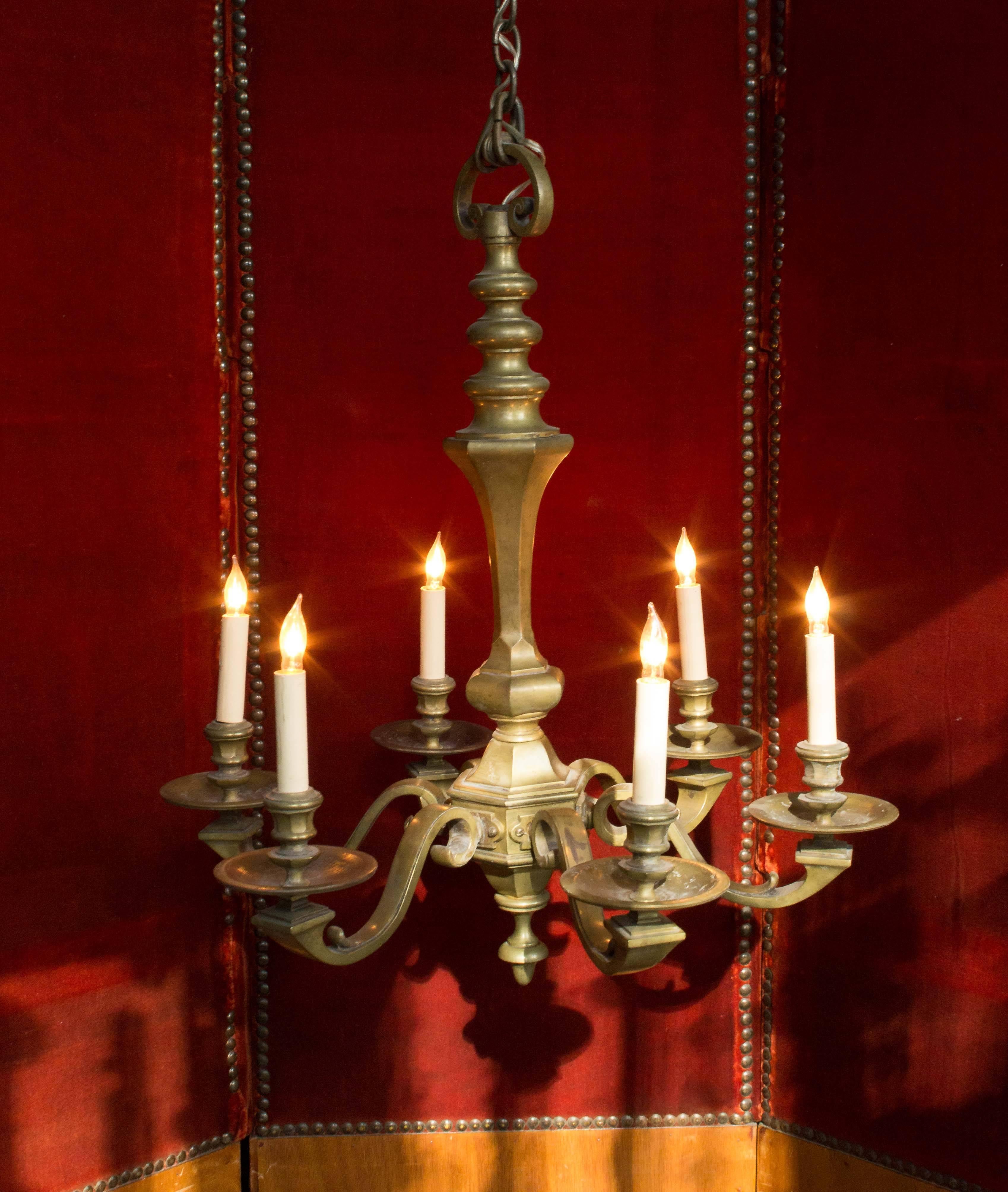 This remarkable French brass and bronze chandelier from the 1940s features six arms in a classic style. The quality of this piece is evident in its robust construction and intricate details. The chandelier has been hand polished to a rich, low
