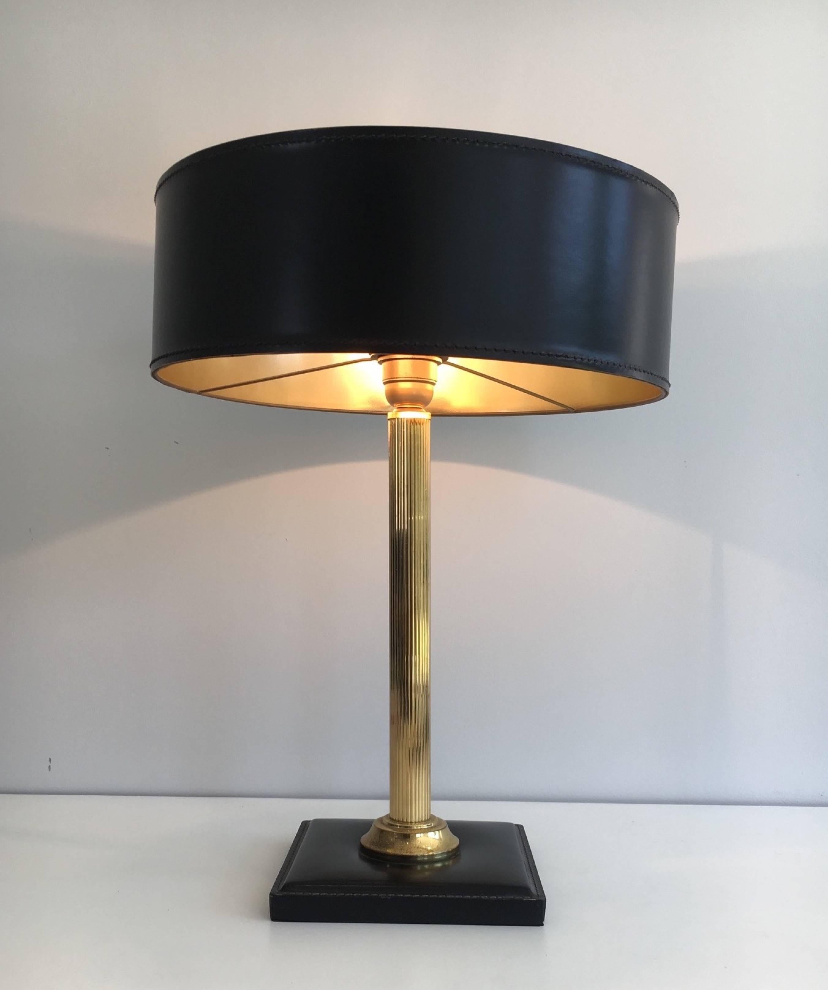 An unusual table lamp in the style of Jacques Adnet. The fluted brass stem is supported on a leather covered base and the shade is stitched leather with gold lining, French, circa 1940.

This lamp is currently in France, please allow 2 to 4 weeks