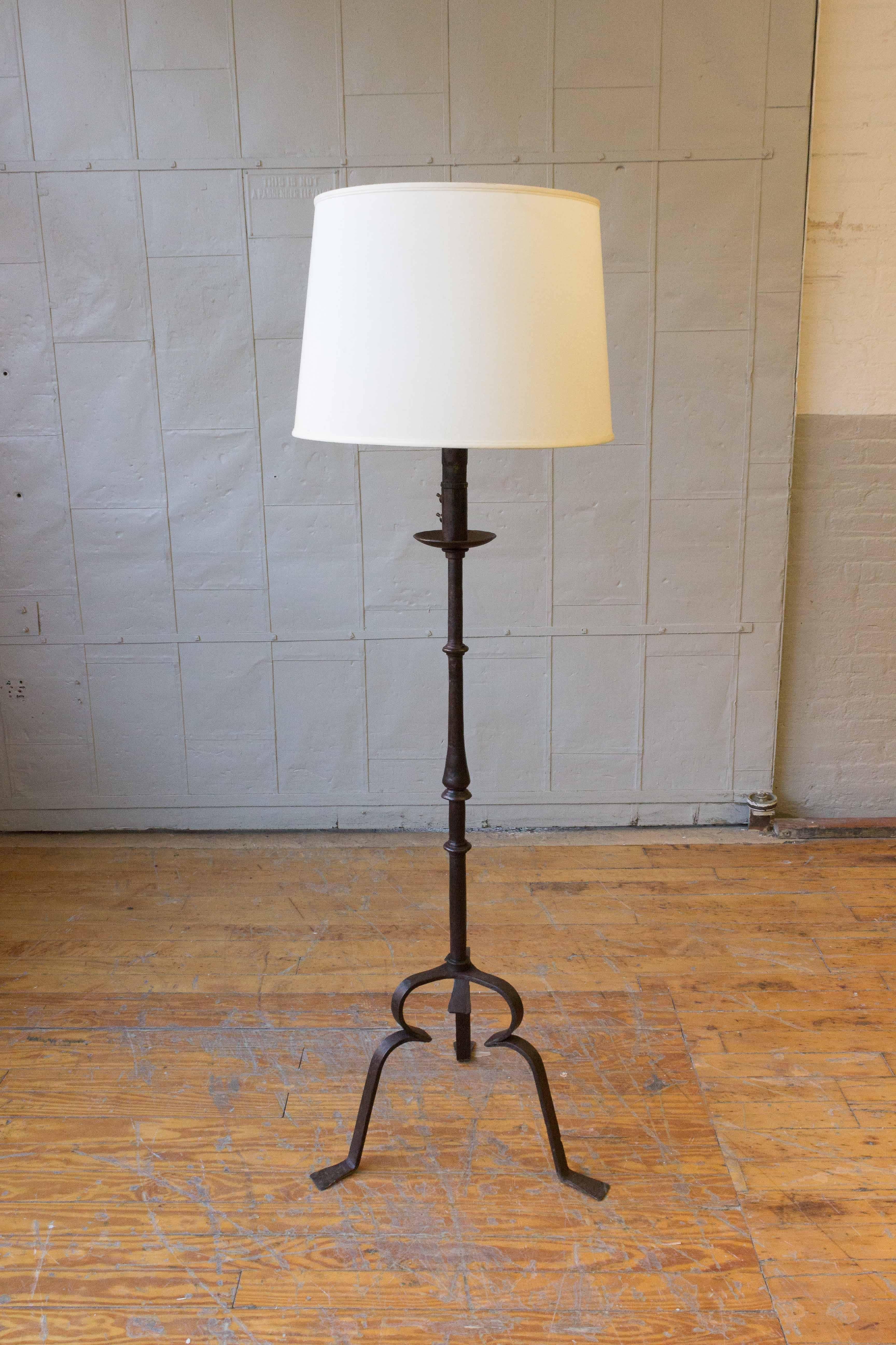 This substantial wrought iron floor lamp exudes elegance and charm. With a weighty feel and sturdy tripod base, the lamp stands tall at 65 inches in height. The iron has a rich patina that adds character and depth to its appearance. The wiring is