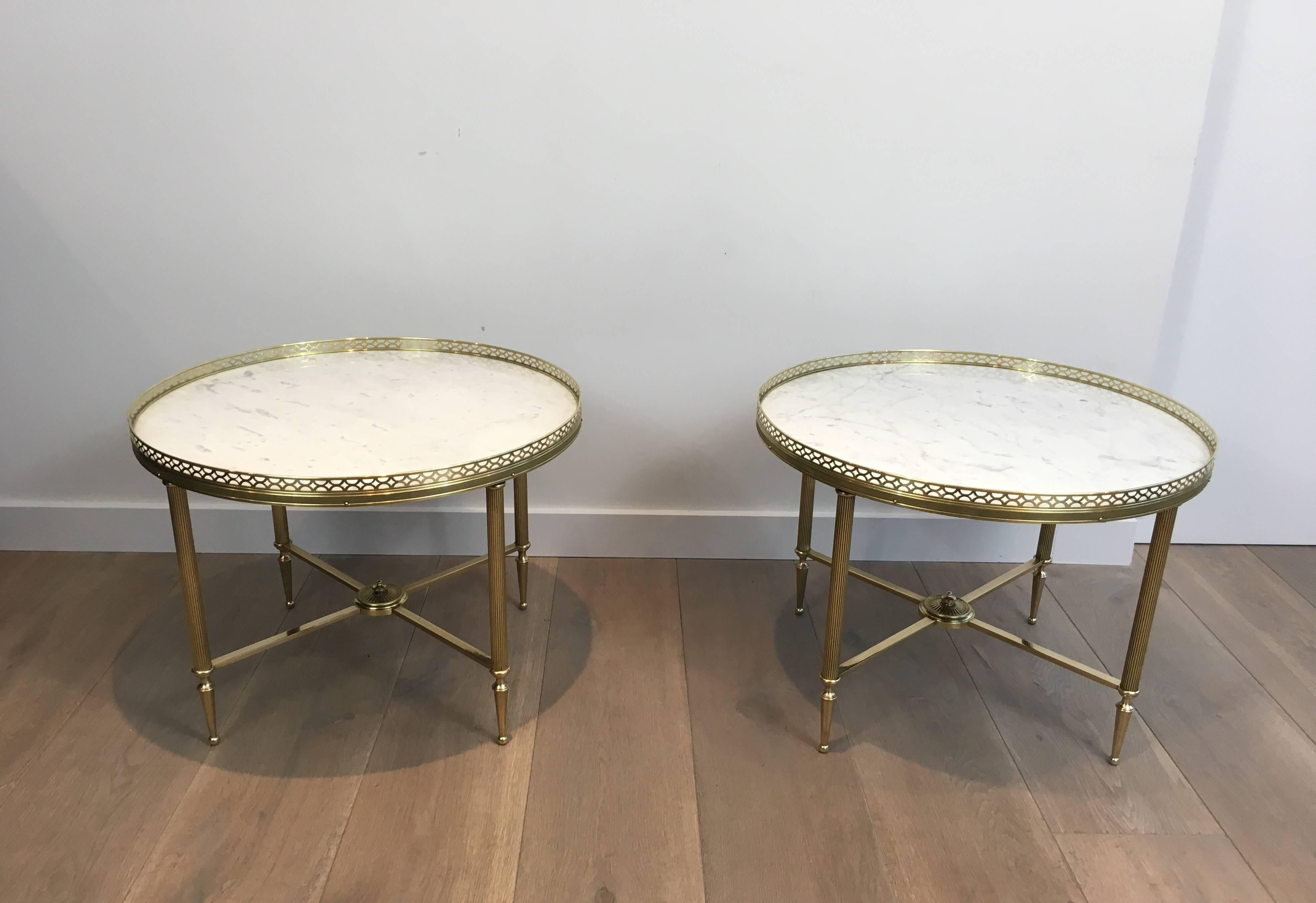 Pair of Maison Jansen neoclassical style brass end tables or coffee tables (17.5 inches high) the white marble tops are enclosed in a brass gallery and mounted on fluted and tapered legs that are joined by an X-stretcher with a centre medallion,