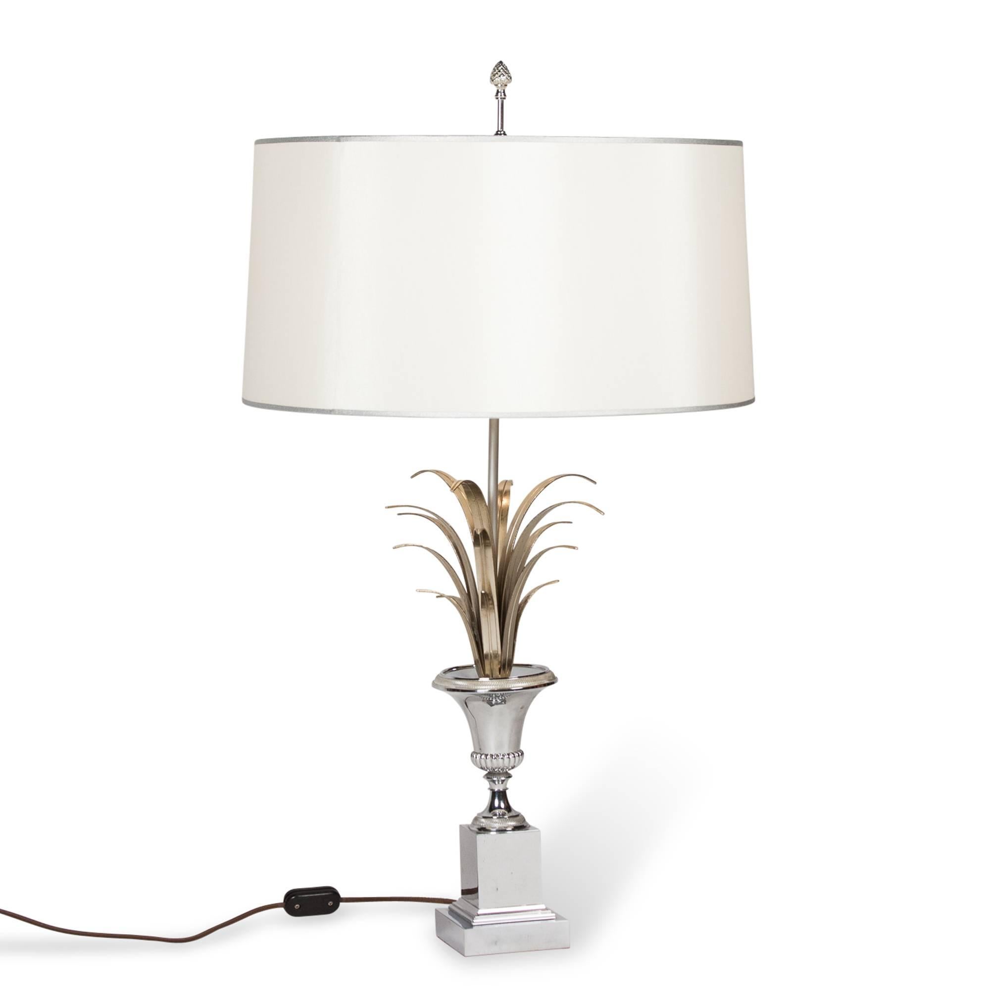 Polished nickel table lamp, of urn form mounted on a block base, with brass leafy elements emanating from urn. In a custom silk shade, by Charles et Cie, France 1960’s. Overall height 30 in, base measures 4 in square, shade diameter 18 in. (Item