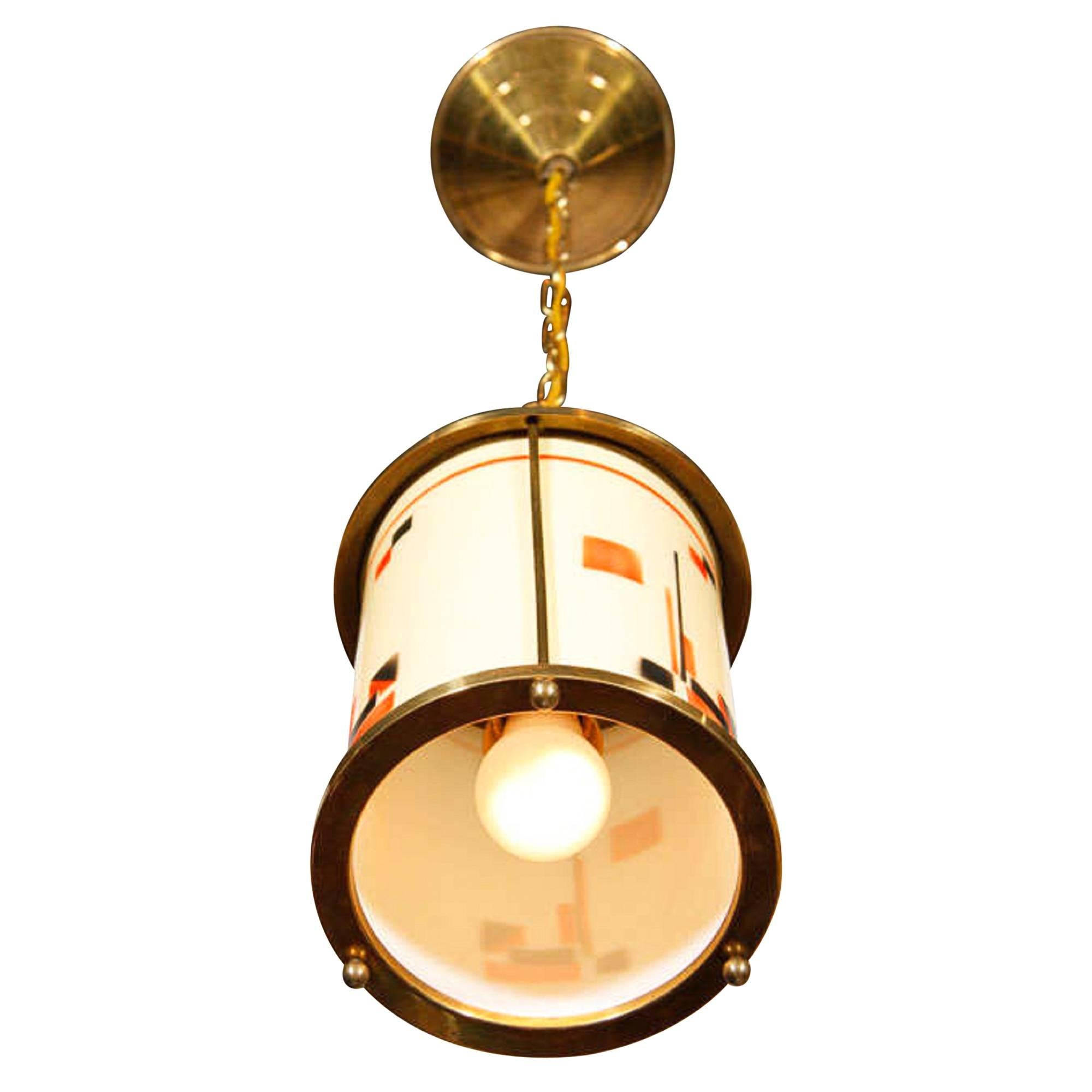 Hanging lamp, the glass shade decorated with Art Deco motifs, of cylindrical form with bronze top and bottom rings, German, 1920s. Suspended by a chain from the ceiling canopy. Measures: Fixture diameter 6 3/4 in, height of fixture 8 in. 
          