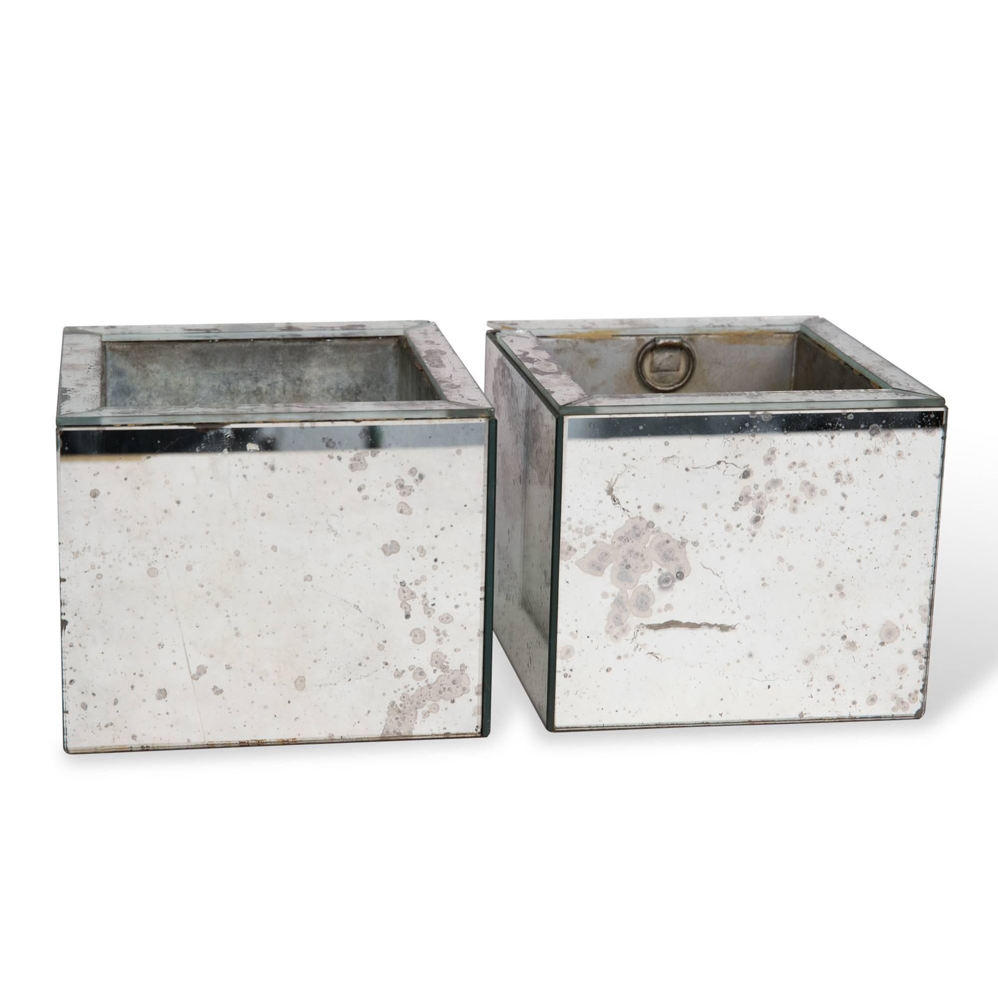 Pair of antiqued mirror planters, with metal liners, metered corners, United States, 1960s. Measures: Larger measures 6 1/4 in square, smaller six in square. Height of each 5 in. 

Note: Loss and crack to corner of one planter.