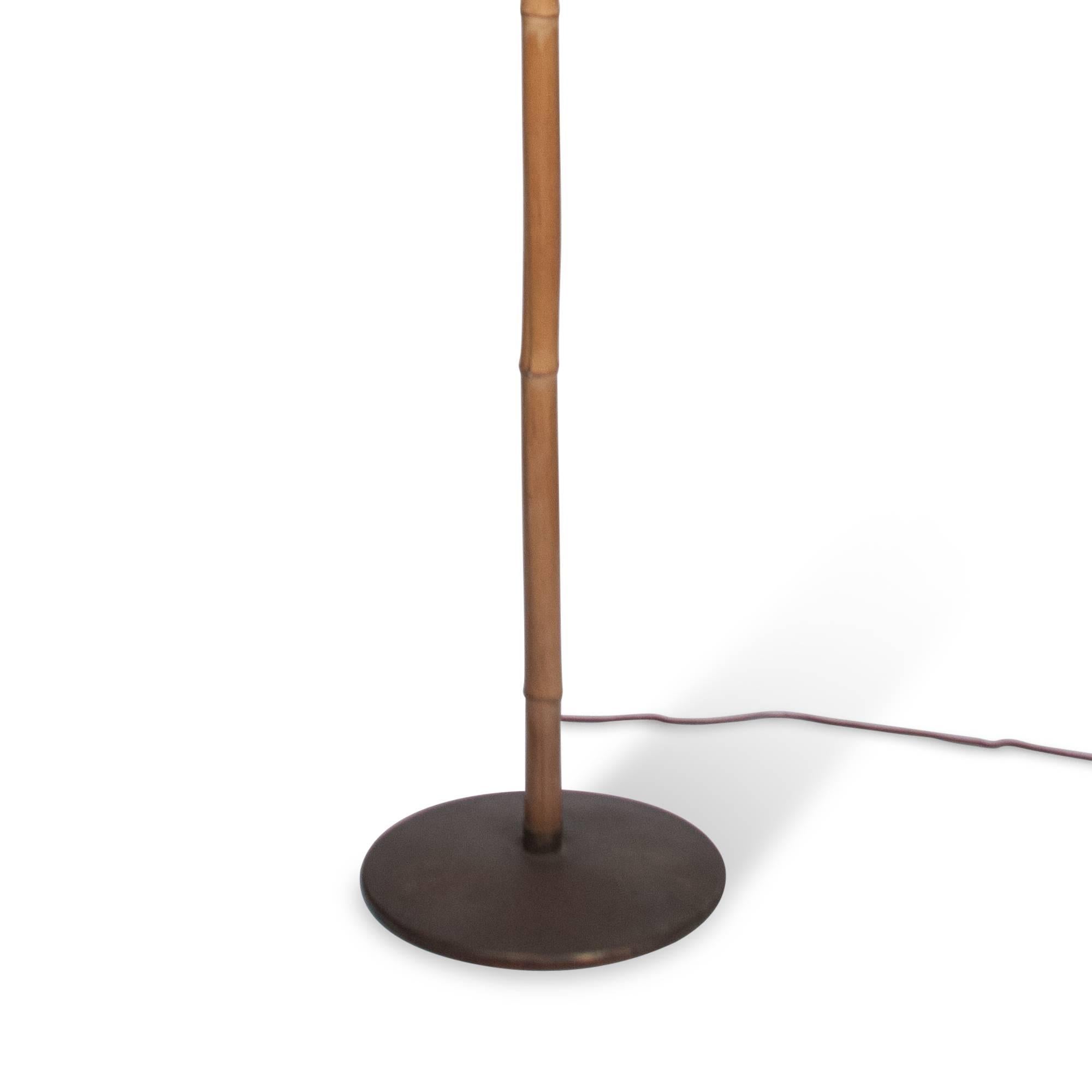 Bamboo floor lamp on a bronze base with a conical burlap shade, in the style of Carl Auböck, Austria, 1950s. Base diameter is 12 1/4 inches. Overall height 70 in, shade diameter 25 1/2 in. 

Has two standard Edison-sized original sockets. Takes a