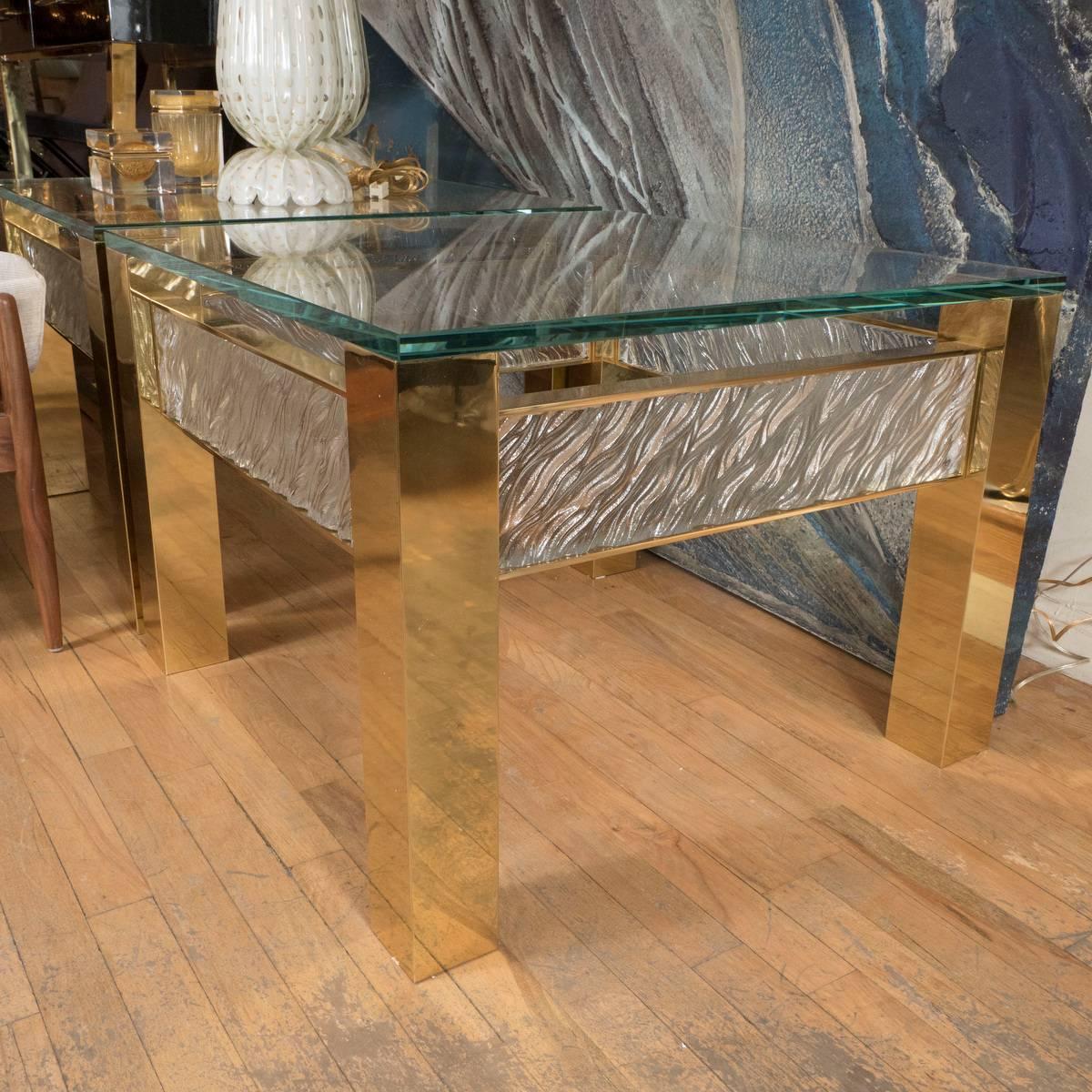 Square brass side table with textured glass banding and glass top designed by John Salibello. Sold individually.