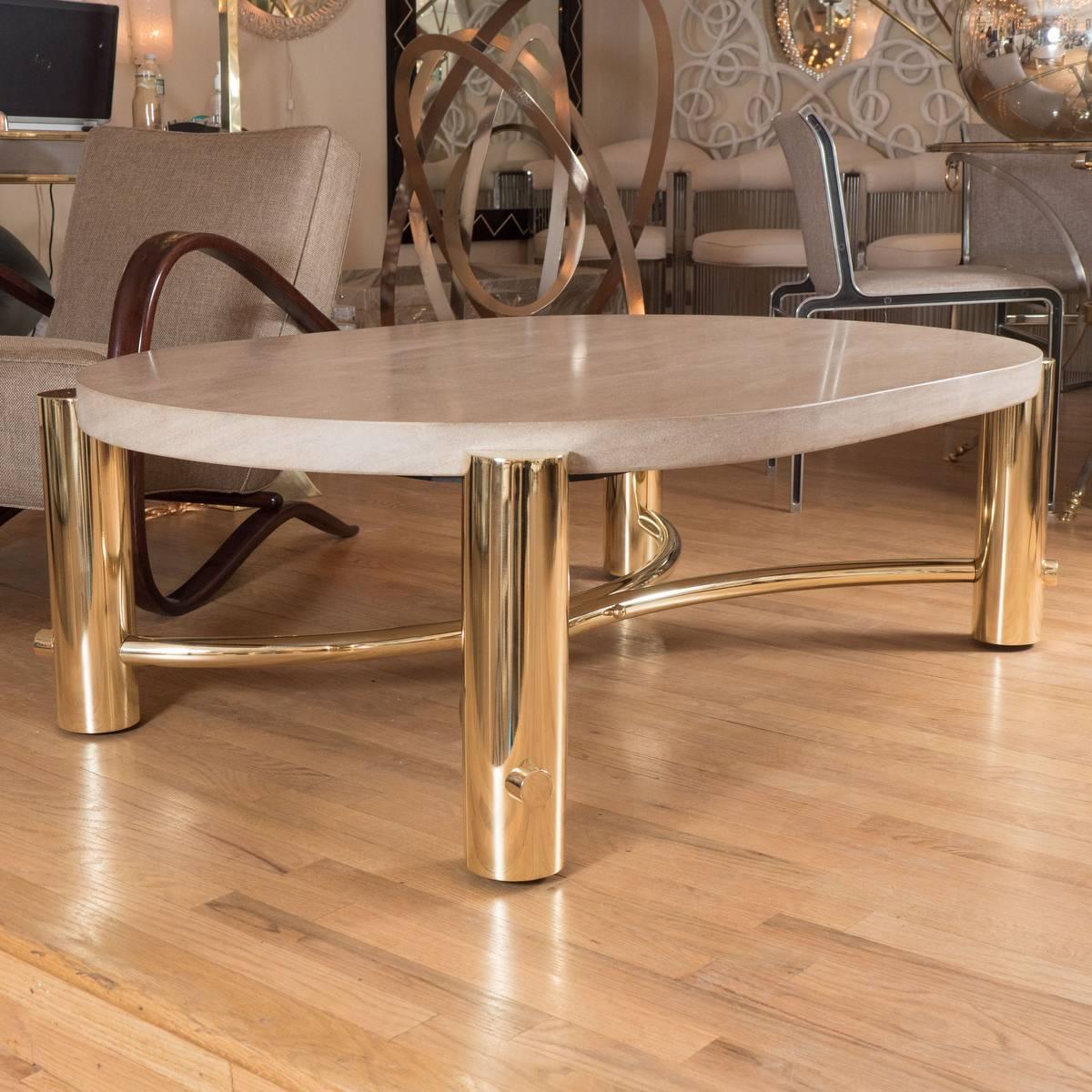 Elliptical coffee table with tubular brass frame and stone top.