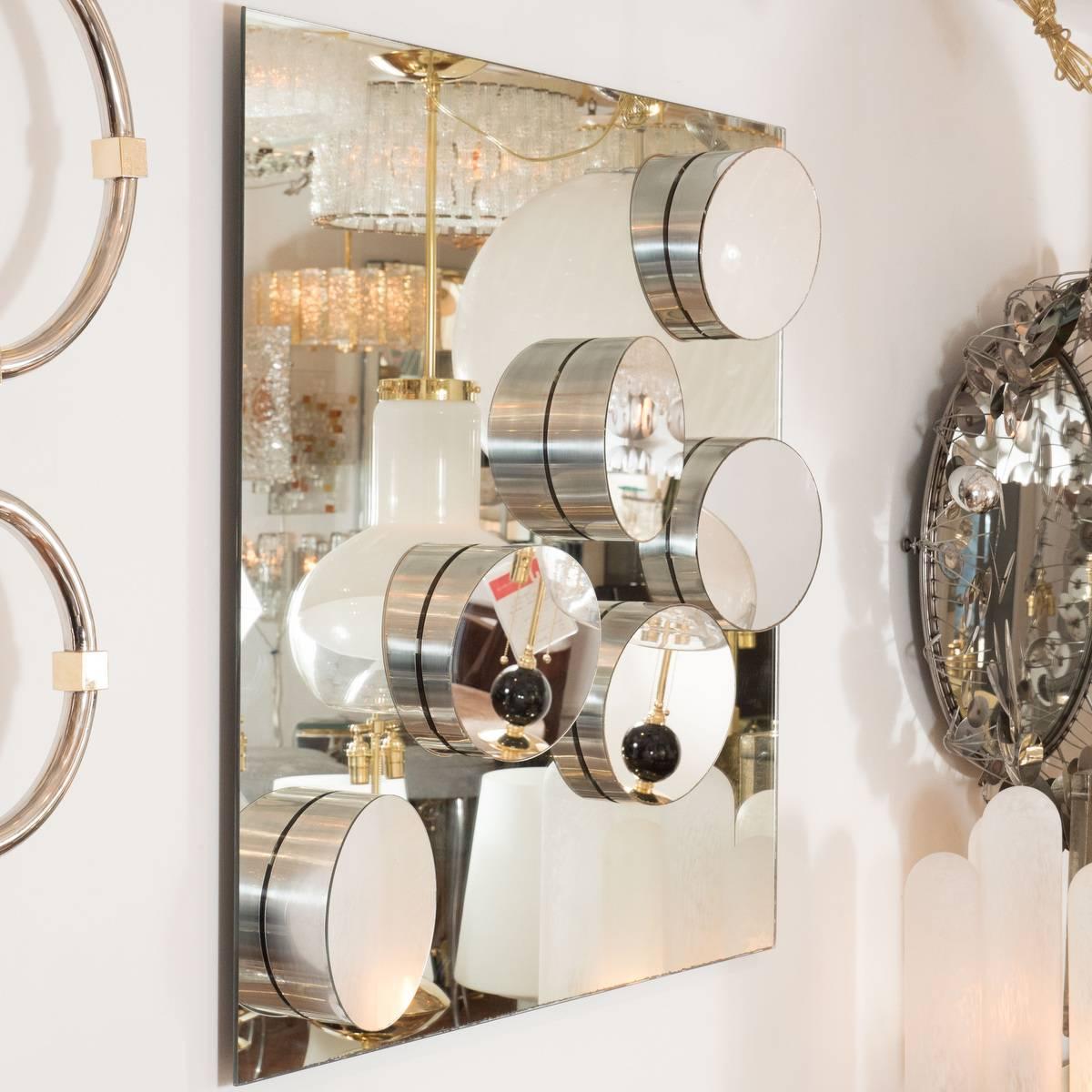 Decorative mirror with applied, sloped details featuring stainless steel frames.