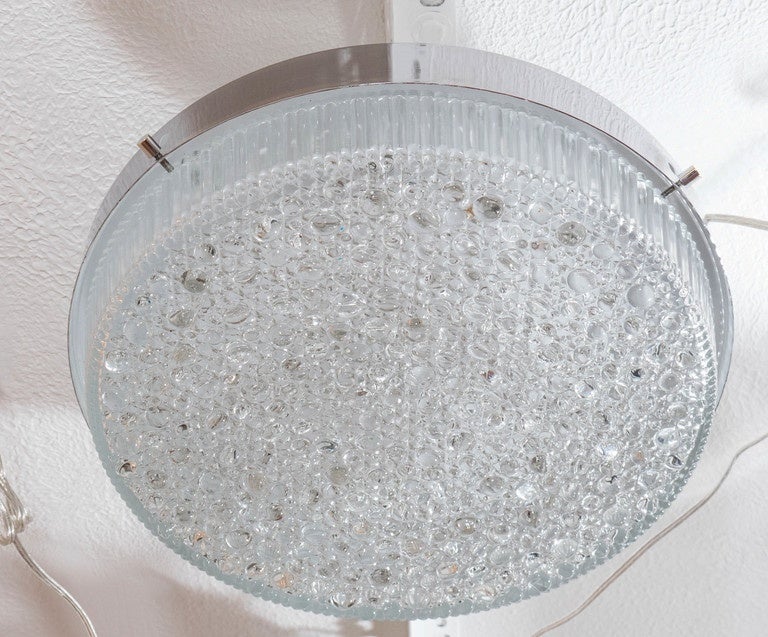 Round polished nickel flush mount fixtures with textured, geometrically patterned glass shade.