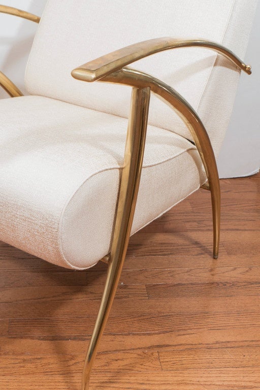 Single, upholstered armchair with stylized brass frame.