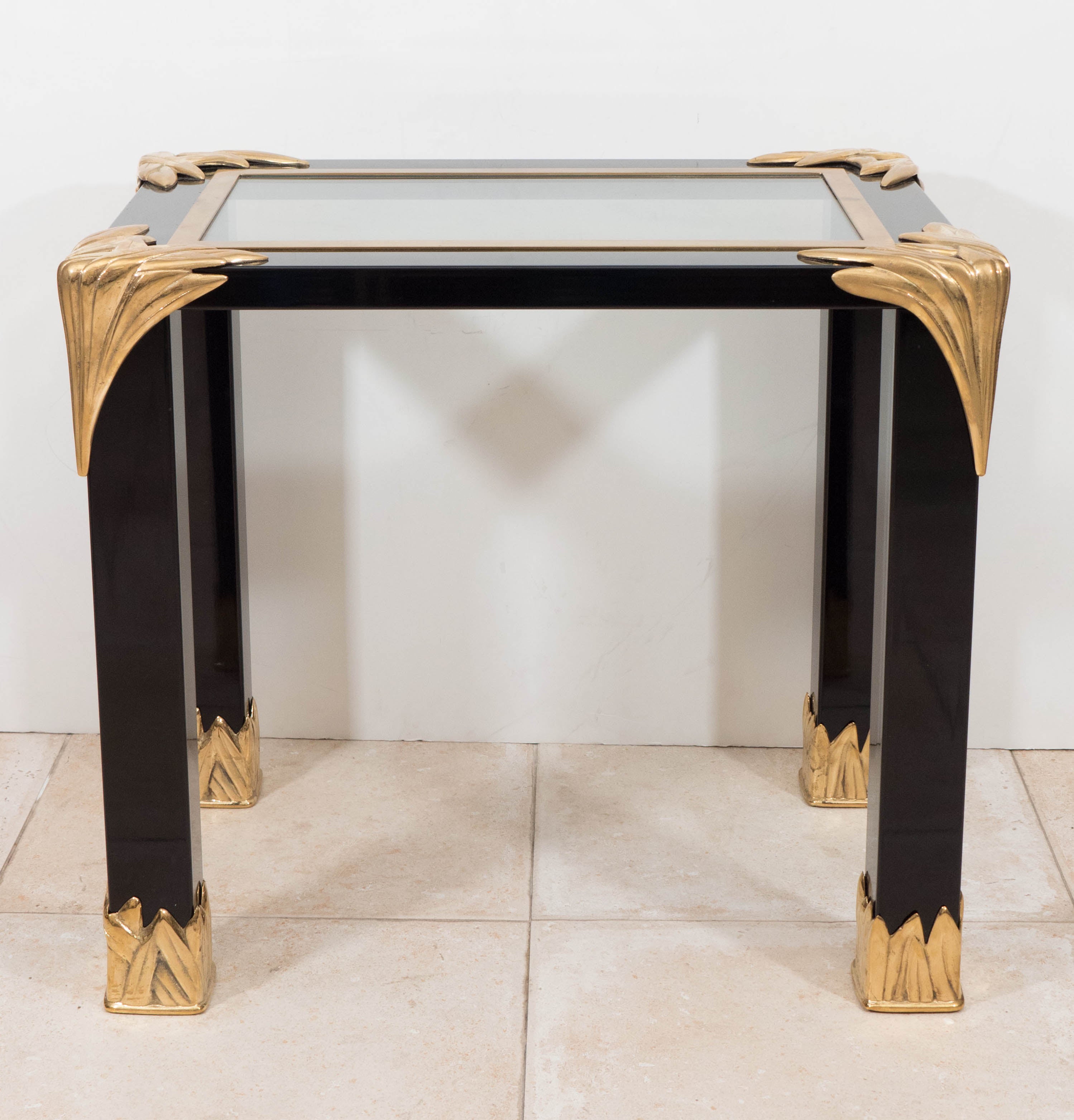 Pair of black lacquered wood and glass side tables with decorative brass feather details.