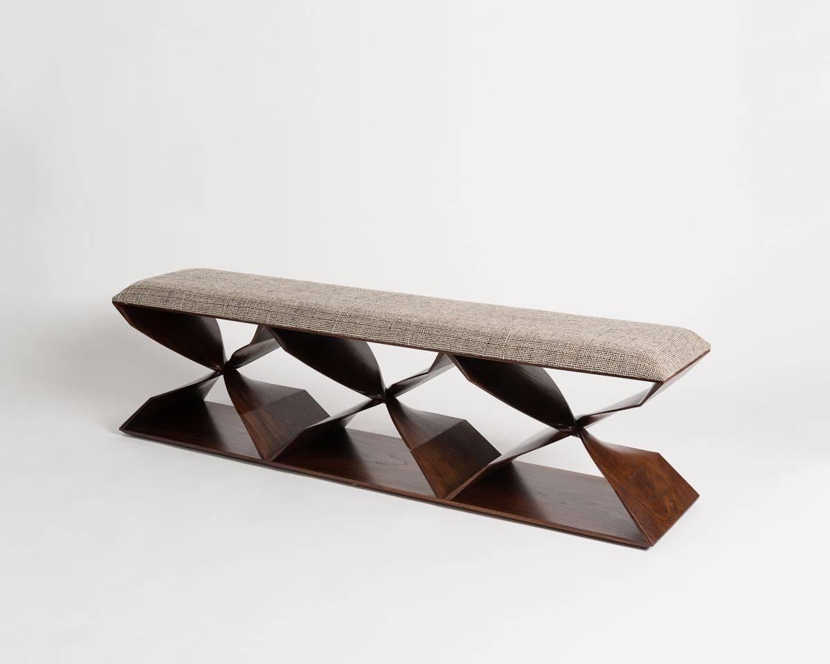 This sculptural hand-carved bench is part of a line of contemporary furniture designed by blending digital technology with fine traditional craftsmanship. Carved of mahogany, the stool features six crisscrossing buttresses, which, twisting 180