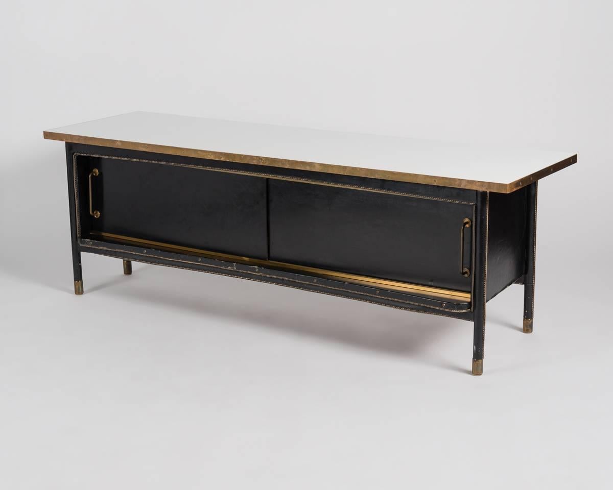 This unique, black leather bar cabinet has an elegantly asymmetrical form, sliding doors, vents for hidden speakers and its original white laminate top.