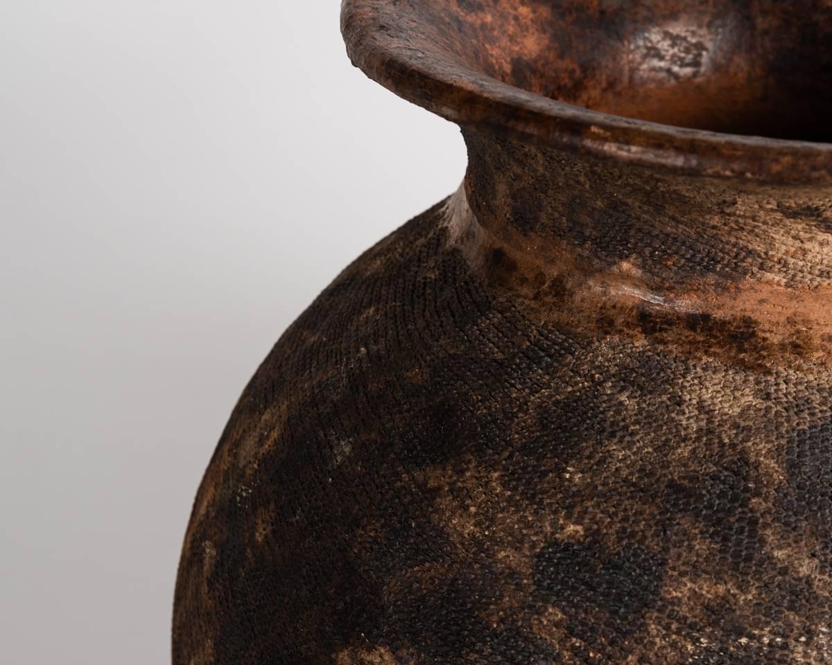 One of several ancient vessels, dating from the bronze age, once held in famed designer Liz Claiborne's private collection, this piece features a flared rim, and an intricately cross hatched texture.
