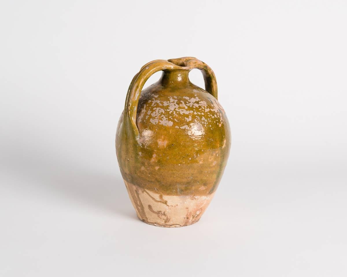 A ceramic jug hailing from Central Europe, and created in the mid-19th century, this piece, which was once held in famed designer Liz Claiborne's private collection, has two handles which extend over its narrowed rim like arms extended.