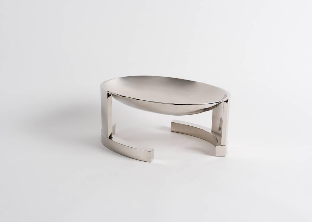 Ivanny, a nickel-plated centerpiece by master silversmiths Juan and Paloma Garrido of Spain, is a convex bowl that stands atop two semi-ovular legs. The legs, which circle one another as in a dance, play with our conception of space, and allow a