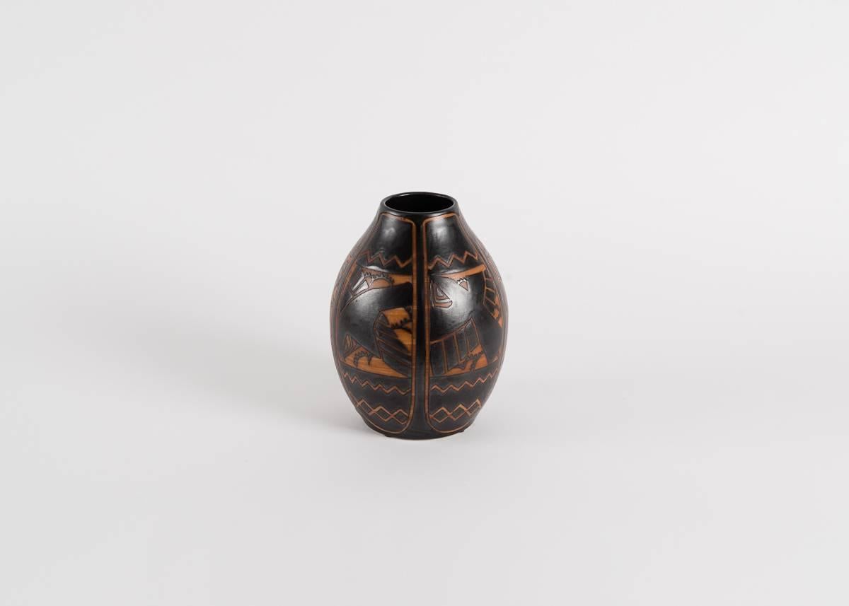 Diese Vase trägt das Catteau-Muster D.1009 mit Vögeln vor stilisiertem Laub, das auf Feldern mit ausgeprägt geometrischen Formen ruht. Das Design ist, wie andere von Catteau, in die Keramik geritzt und durch Farbe belebt.

Unterschrieben: Ch.