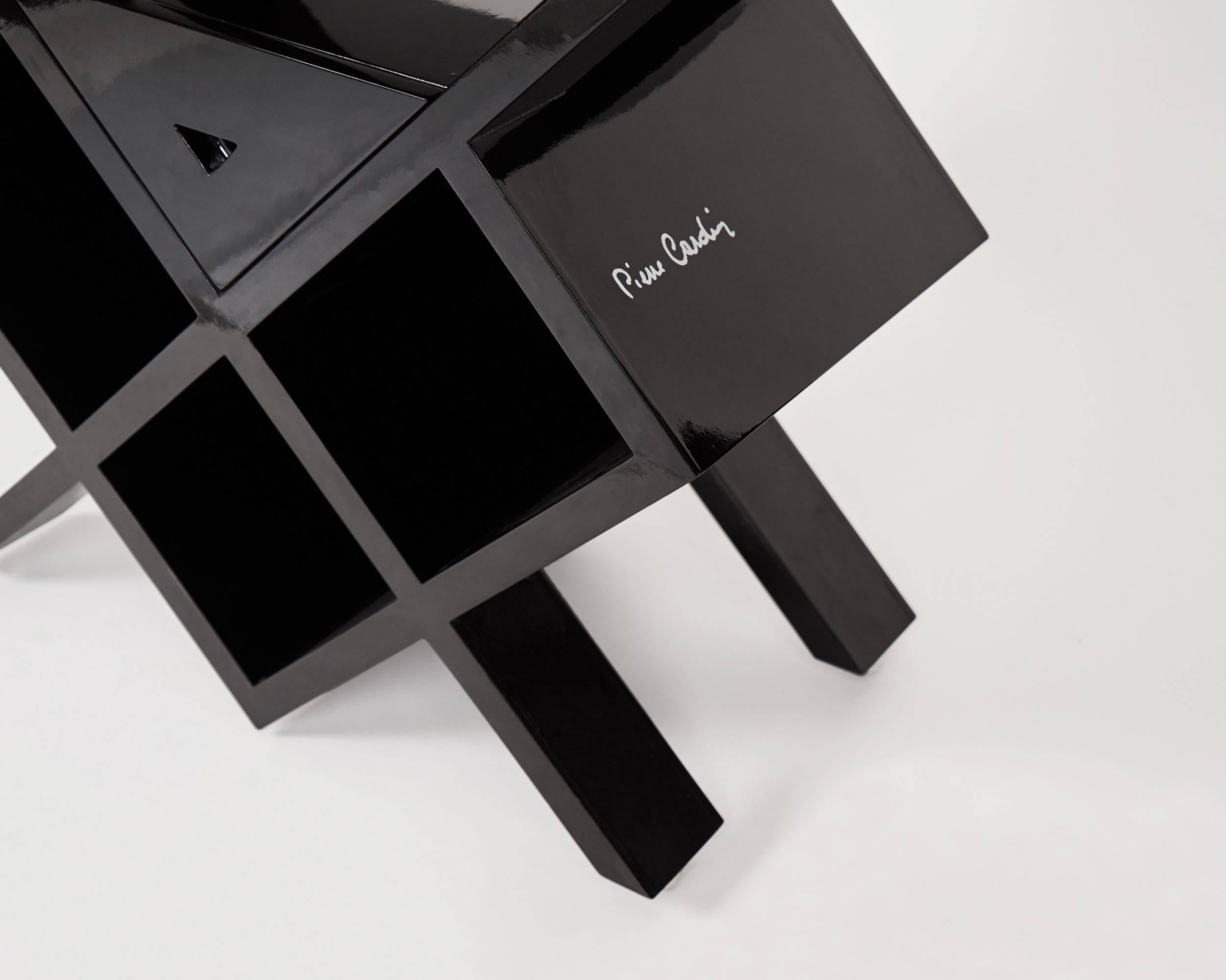 A black, polished side table with shelving by designer Pierre Cardin.