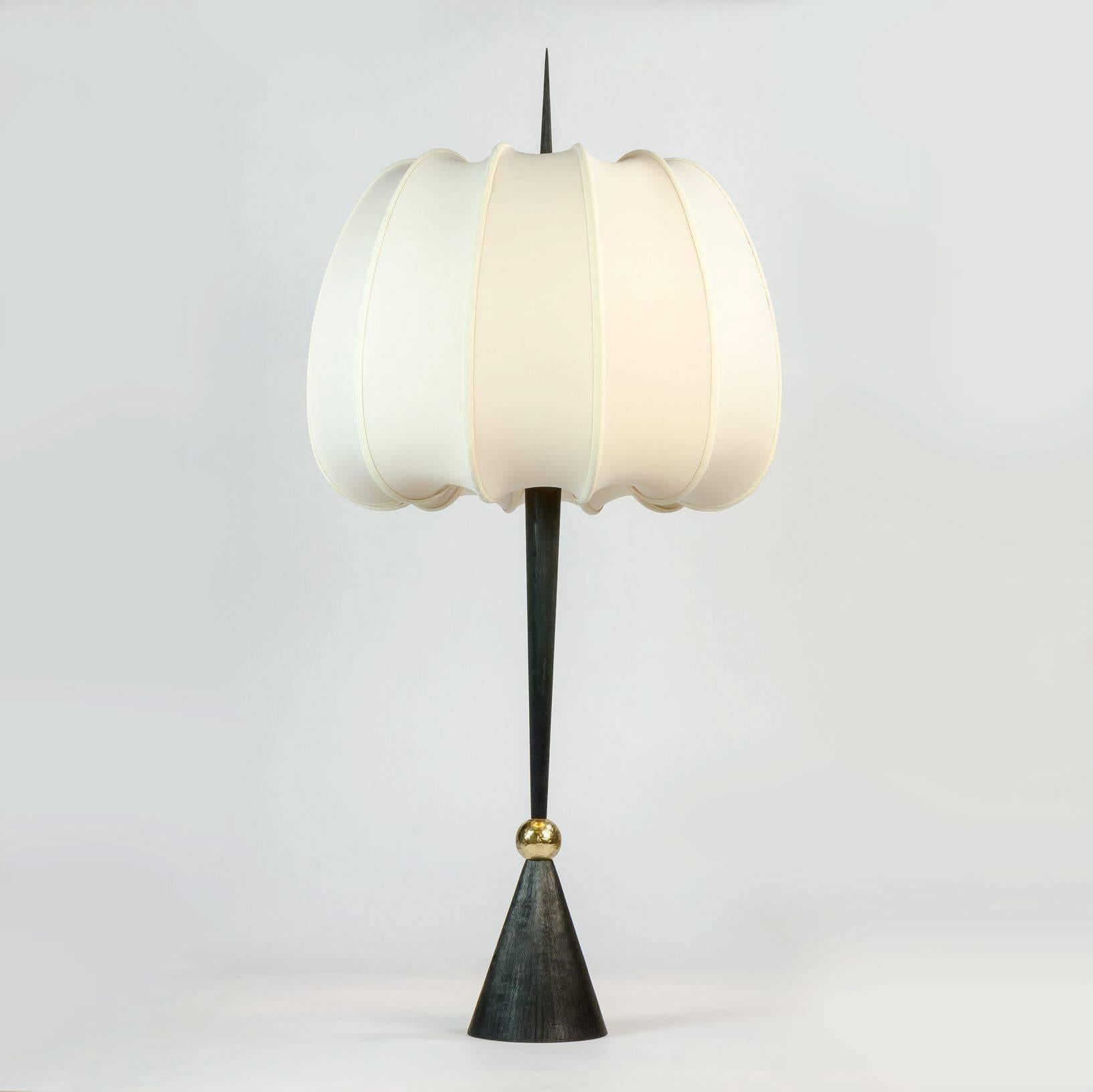 One of Achille Salvagni's most arresting pieces, Lancea features a conical base topped with a brass ball, a burnished bronze 'lance,' and silk shade ribbed in such a way as to create the illusion of inflation. 

Limited edition of 10.