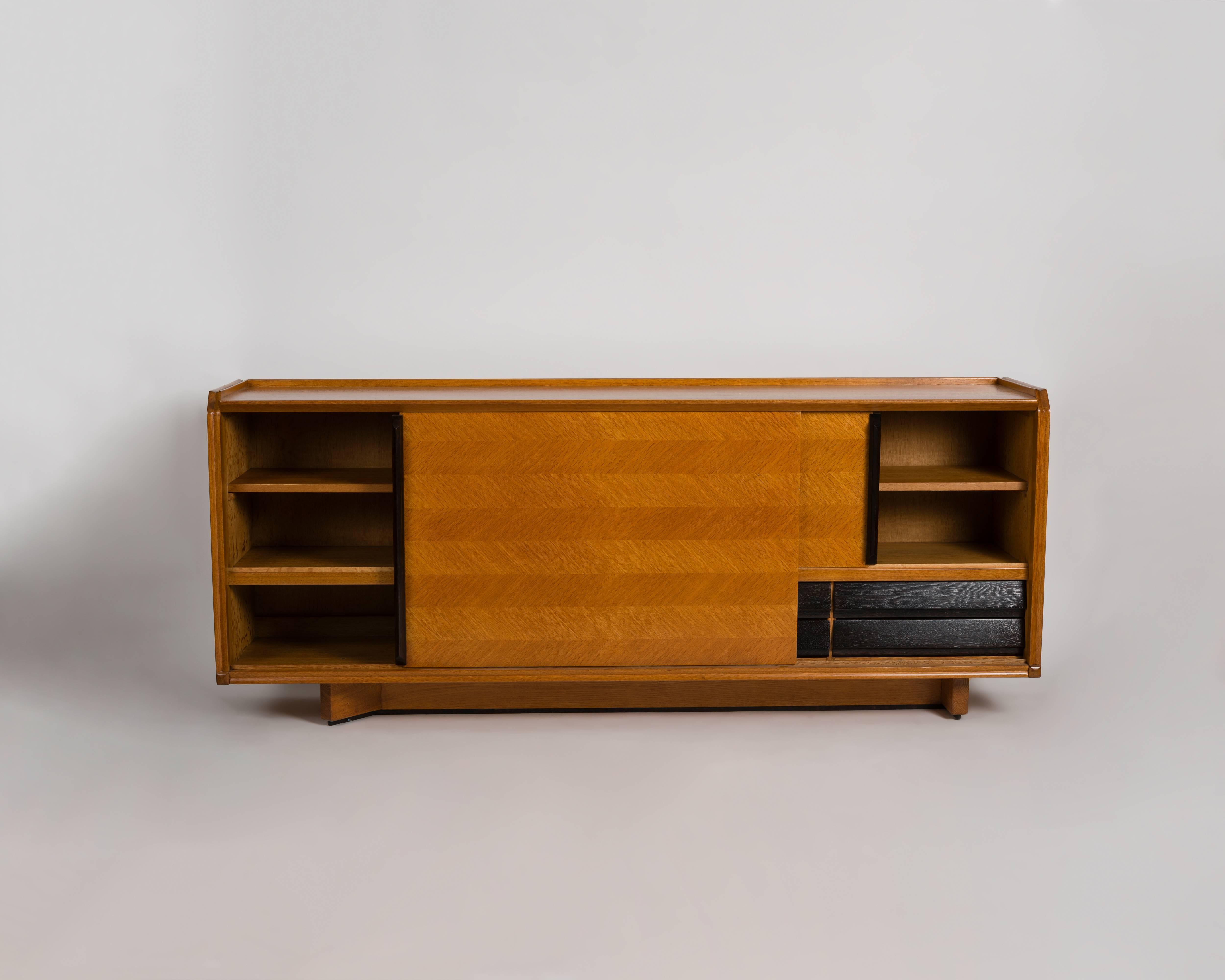 This midcentury buffet in a light, veneered oak has sliding doors and drawers, and was made by the celebrated French designer Robert Guillerme, as part of a line of midcentury design he produced for the company, Votre Maison.