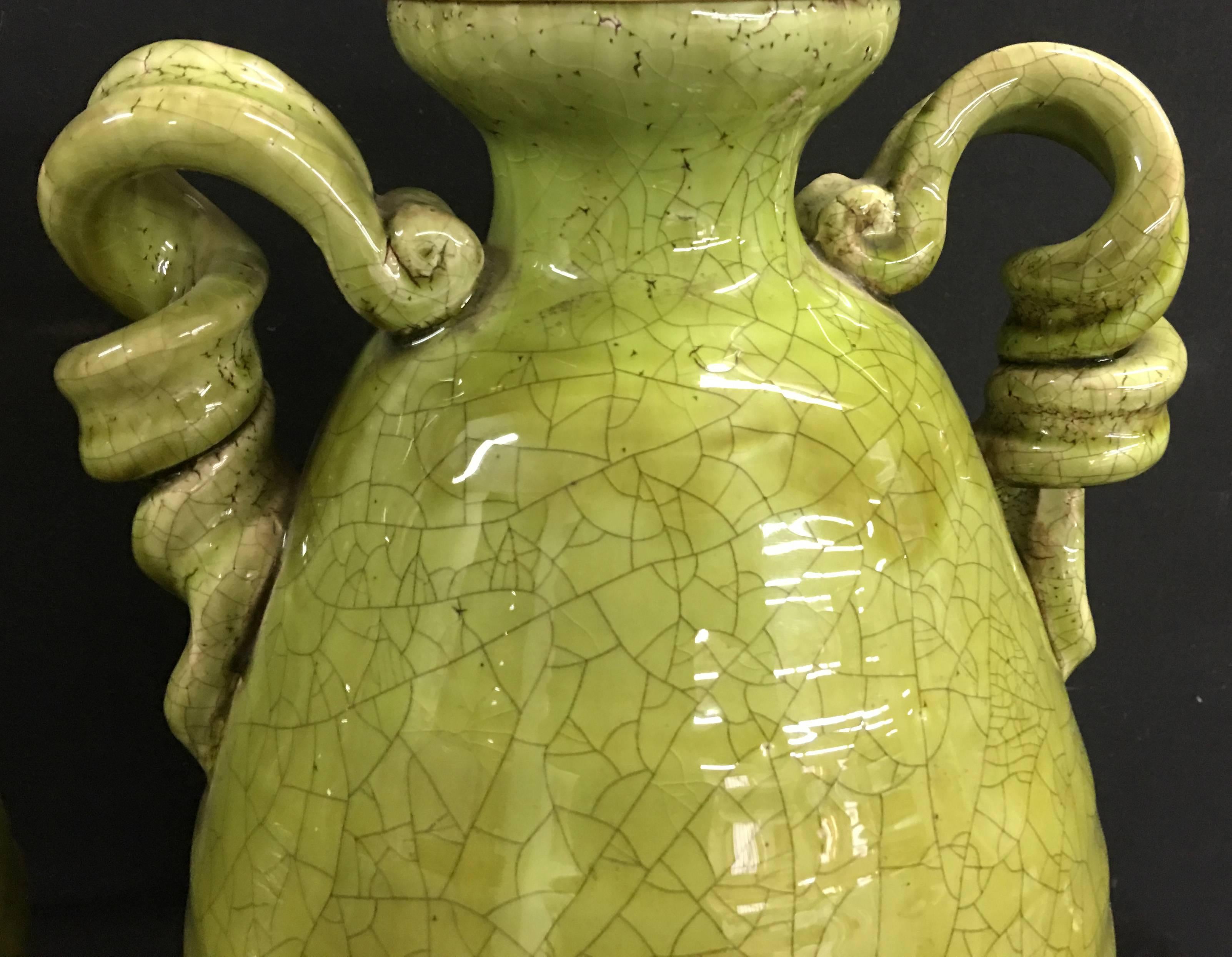 Unusual pair of apple green crackle glazed urns with lamp application. The lamps are newly wired. The hardware is brushed brass with Dual sockets and individually controlled pulls. The vessels are 14" in height, the shade post is 26" with
