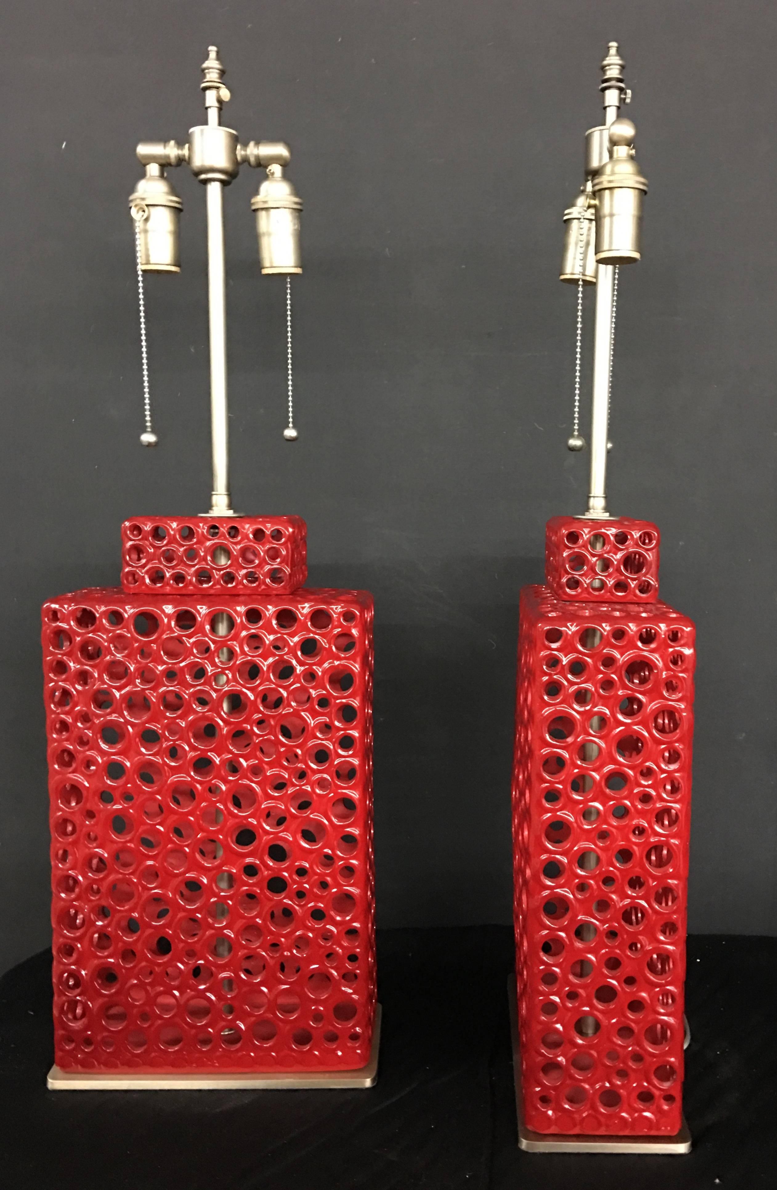 Unique pair of red ceramic vessels with lamp application. The lamps are newly wired, the hardware is brushed nickel with individually controlled dual sockets. The base is in matching brushed nickel. The vessels are 17