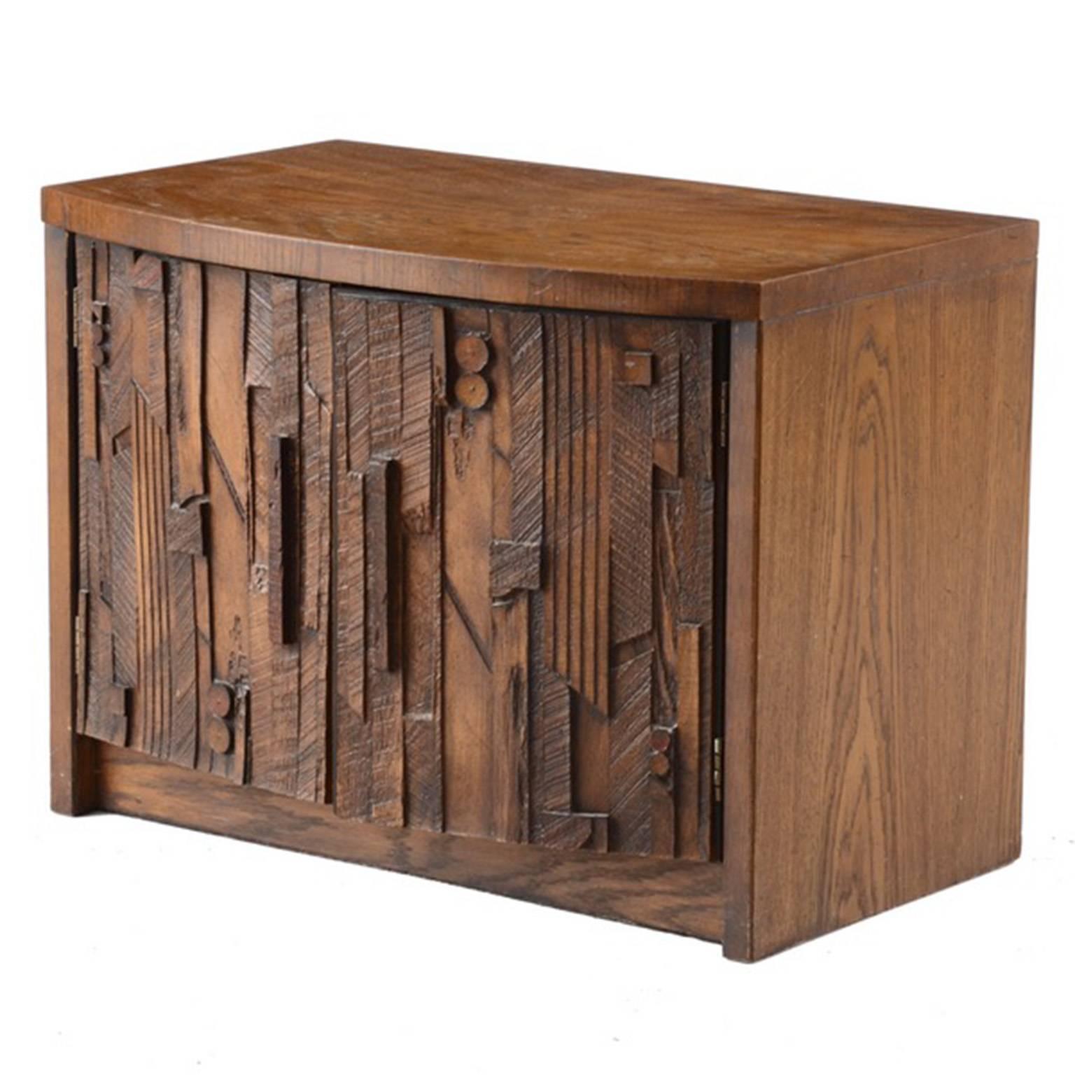 An oak Brutalist nightstand designed by Lane Furniture. The cabinet features an oak veneer top with two doors opening to a shelved interior. The doors have asymmetrically pieced wood fronts, in a Cubist style.