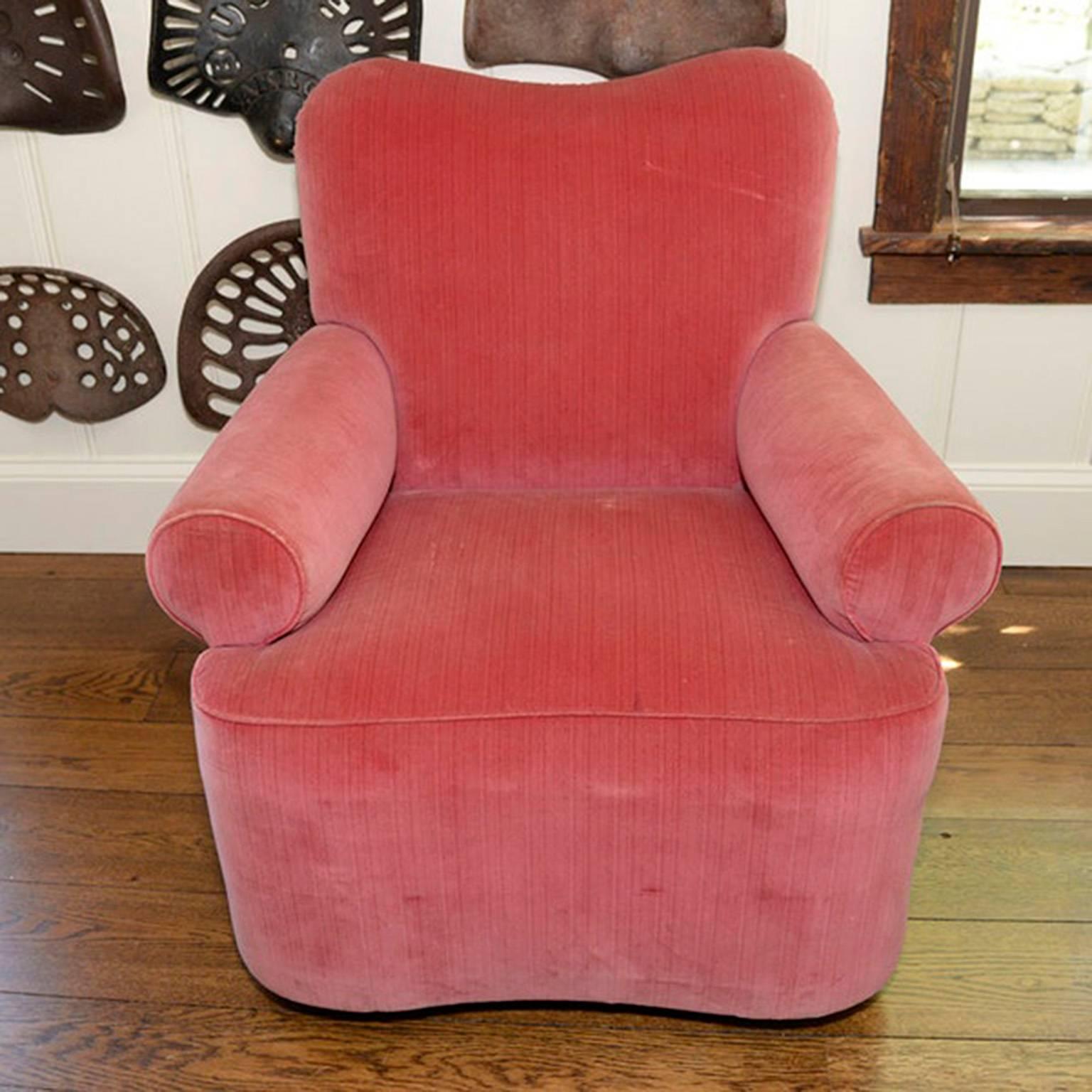 A fuchsia velour swivel chair in Muriel Brandolini style. The unique chair has bolster arms, upholstered in a strie velour fabric with coordinating piping at the seams. Slight wear on the welting.