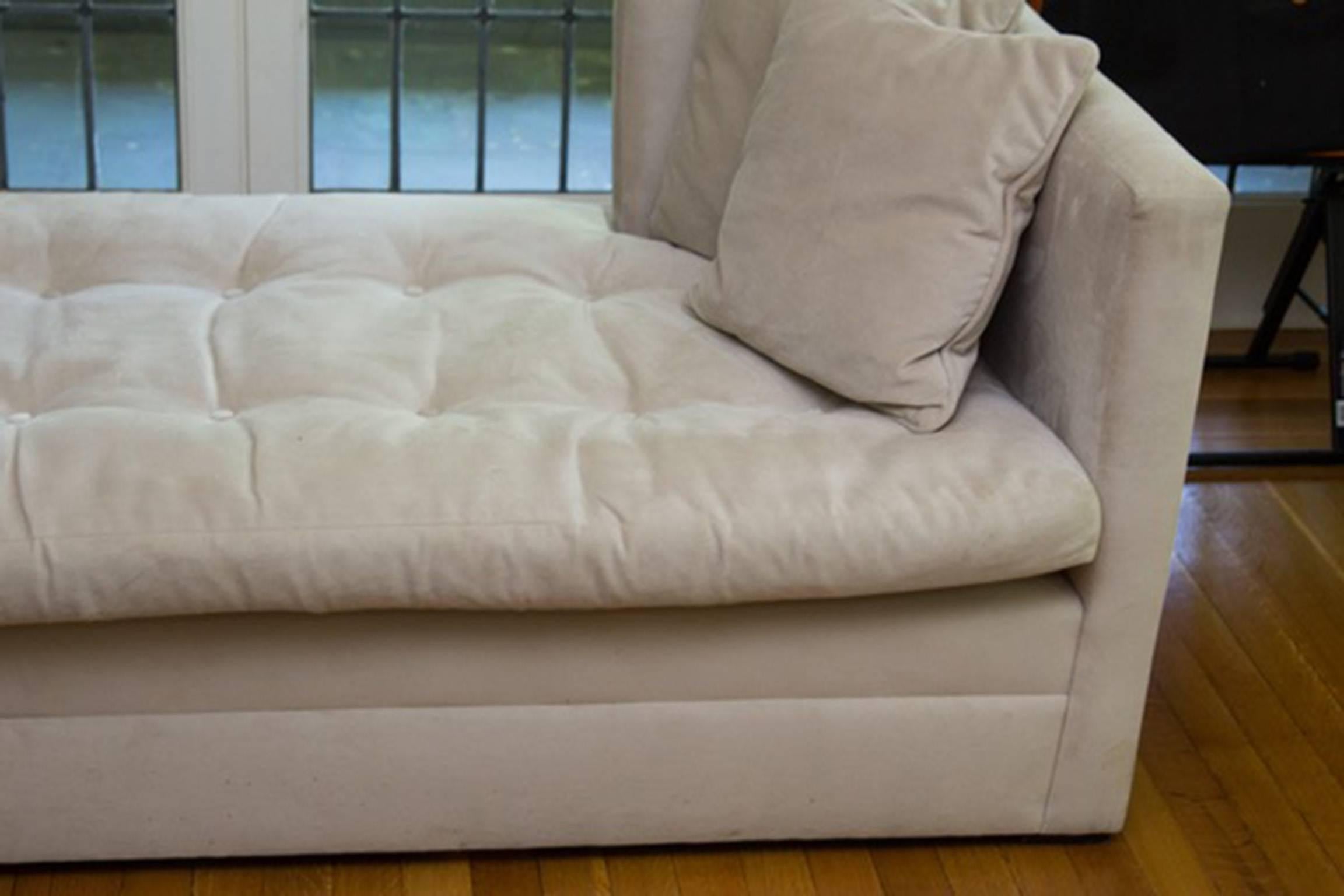 A Bromwell custom, down-filled daybed with pillows. It features lightly padded wraparound supports, a removable button-tufted cushion and block feet. The piece is covered with suede-like beige upholstery. Includes four matching pillows.