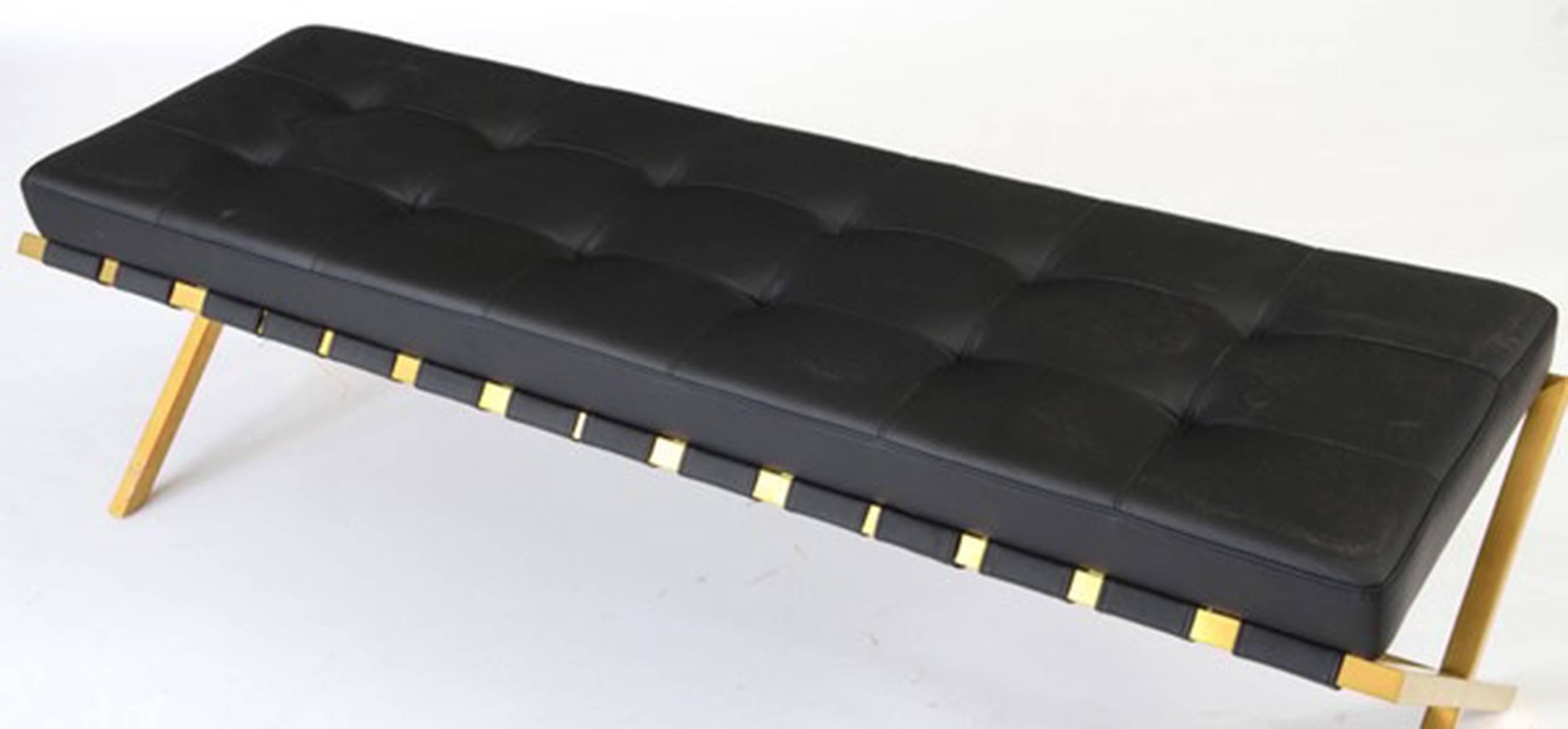 A contemporary Nuevo Living Auguste bench, having stainless steel X-form frame with brushed gold finish and a black vinyl upholstered seat.