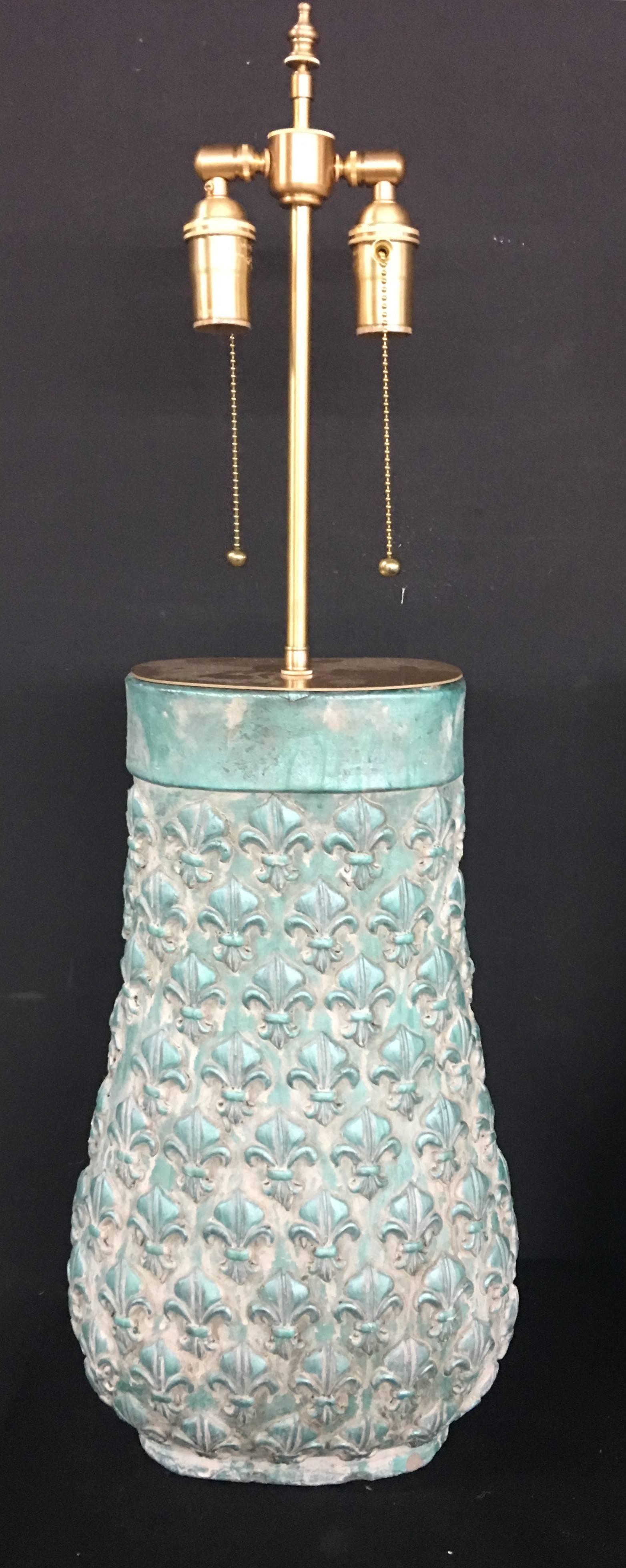 Unusual pair of molded clay vases with lamp application. The vessels have a raised fleur-de-lis pattern in a white wash over a pale blue background. The hardware is brushed Brass. The vessels are 19.5