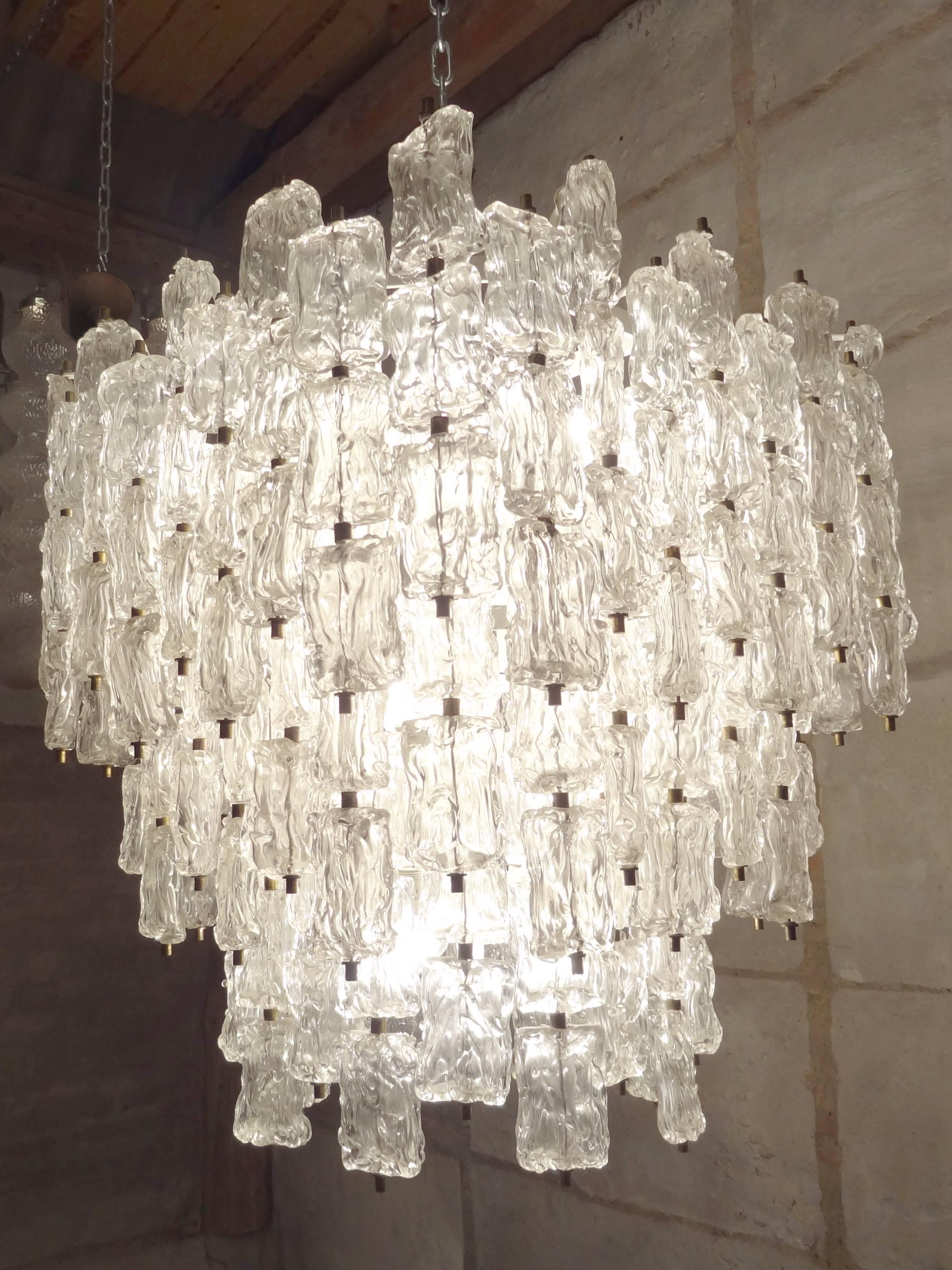 A large chandelier consisting of multiple pieces of textured glass hung from a brass frame by Aureliano Toso.

Italian, Circa 1962