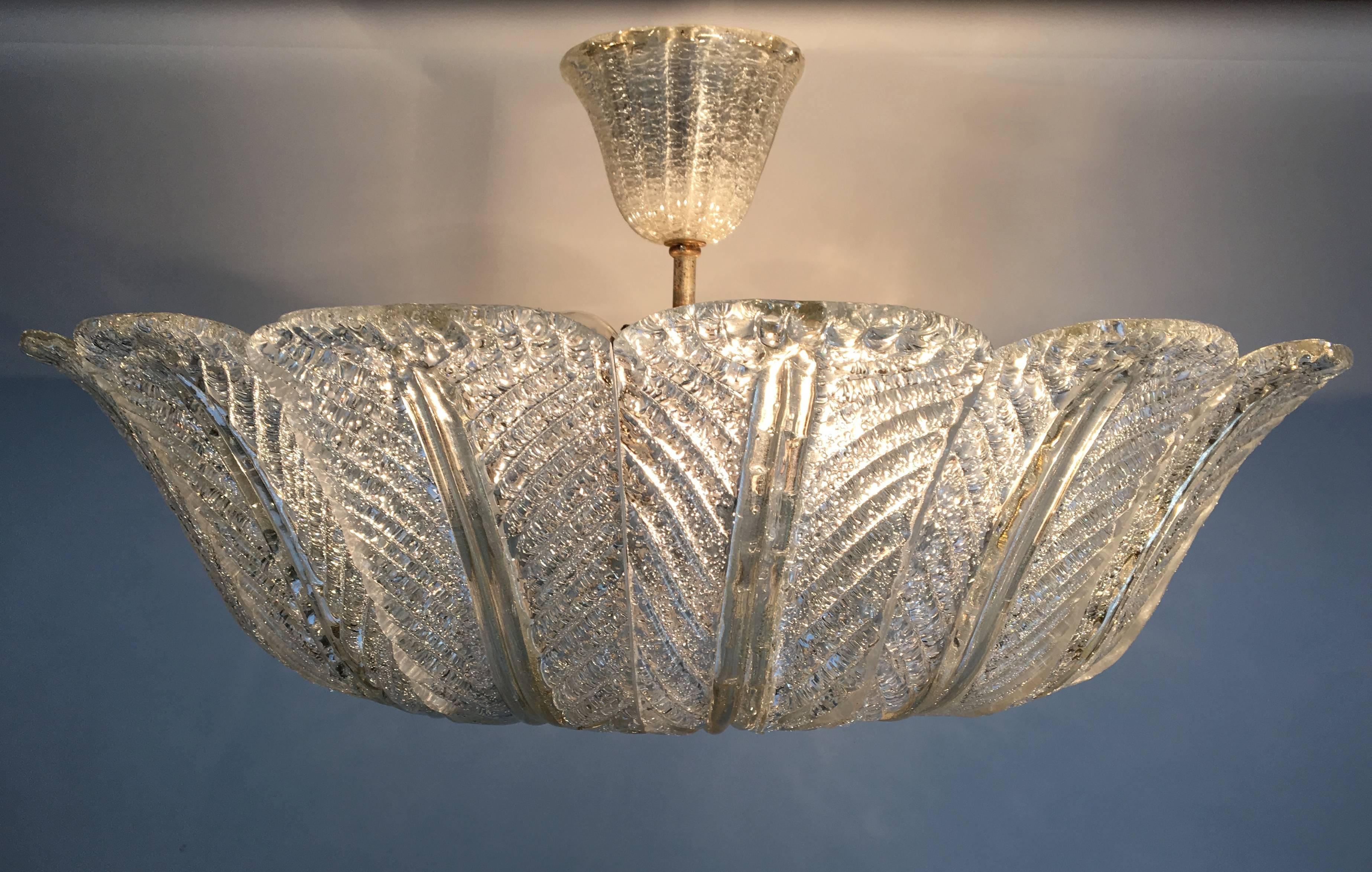 A glass ceiling fixture consisting of multiple panels of textured glass hung around a textured glass disk with brass hardware and glass canopy by Venini.

Italian, circa 1950s.