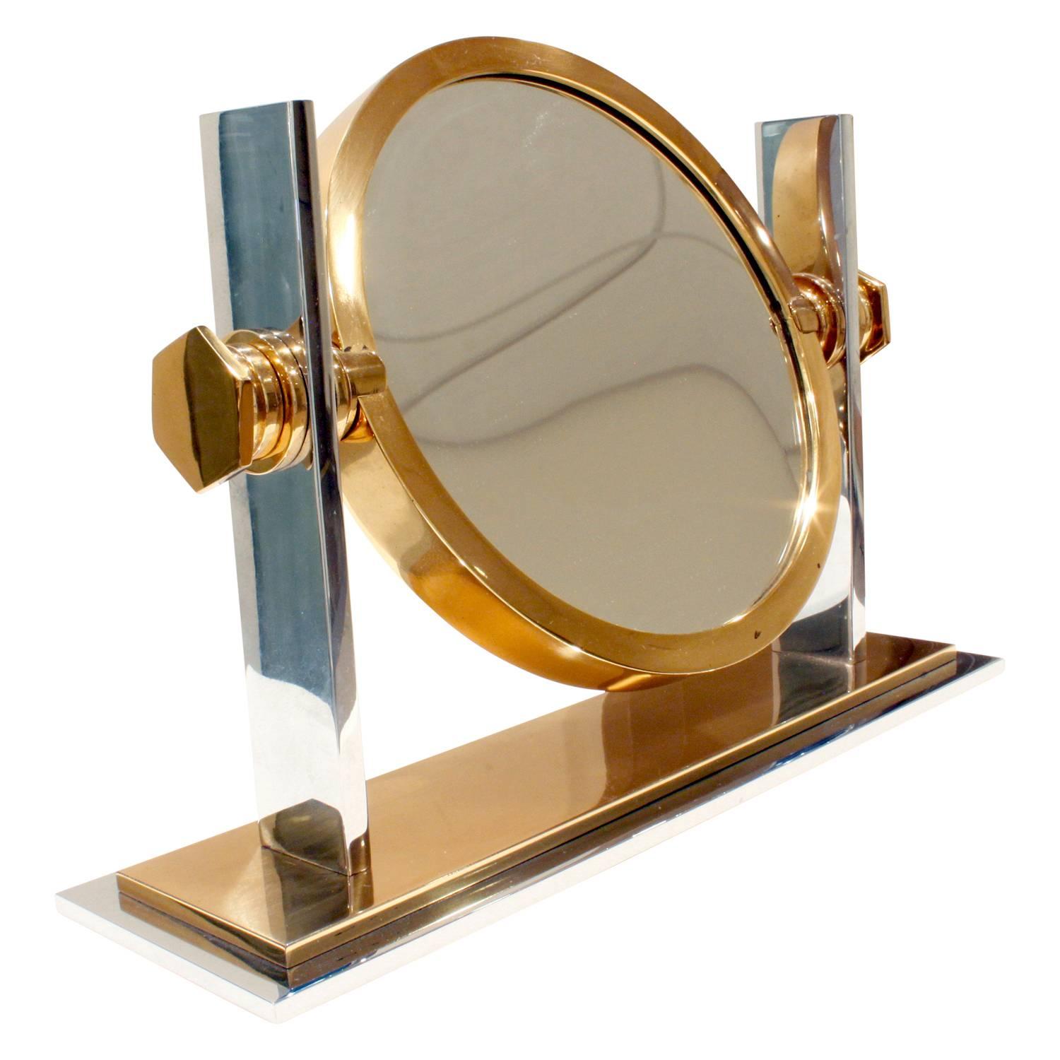 Meticulously crafted vanity mirror in polished chrome and brass with magnifier on one side and mirror on the other by Karl Springer, American, 1980s.