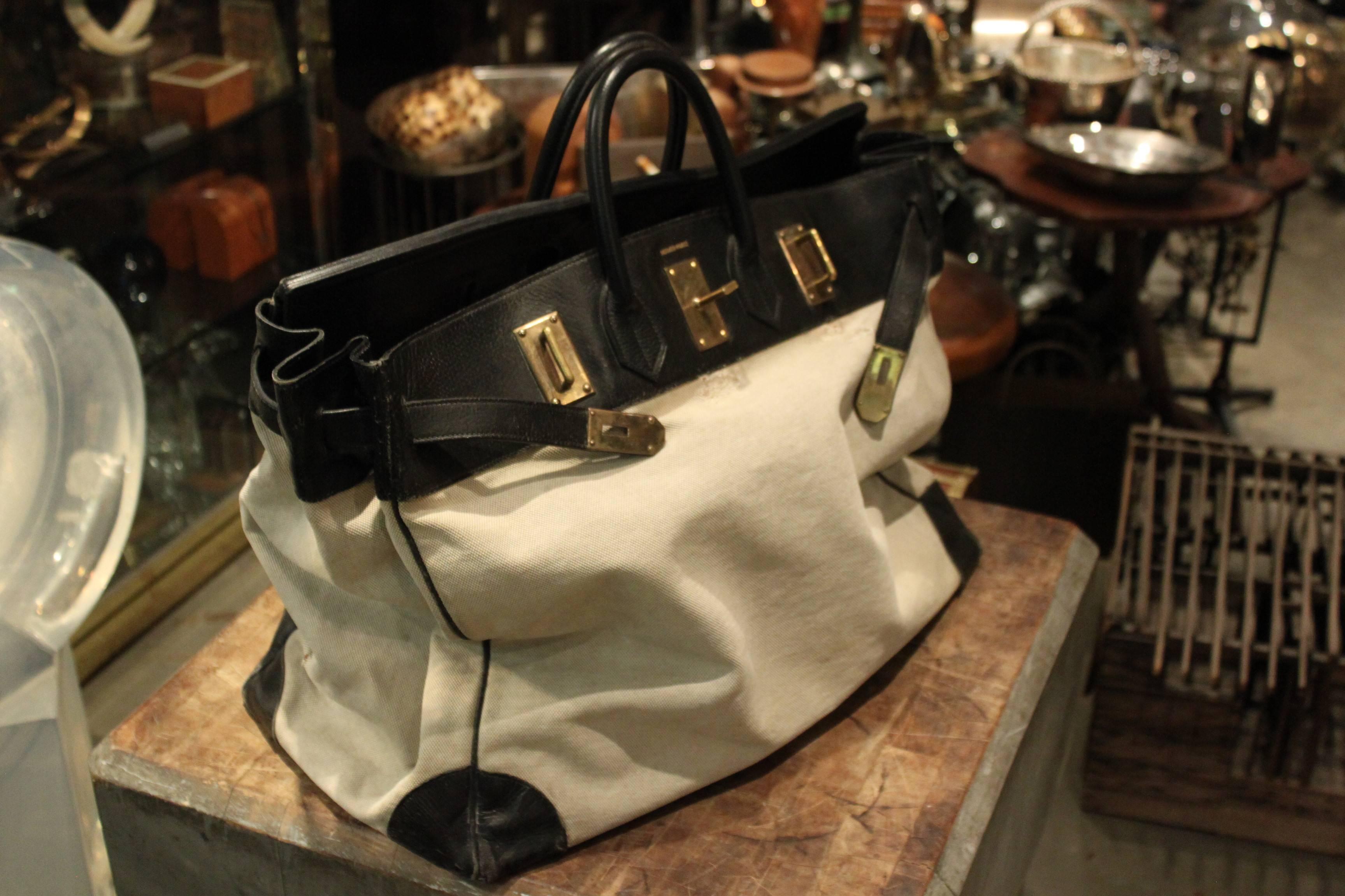 Amazing Hermes 55 cm HAC bag. This bag has perfect wear. It is structurally very strong. Its black leather and white canvas. A great vintage example.