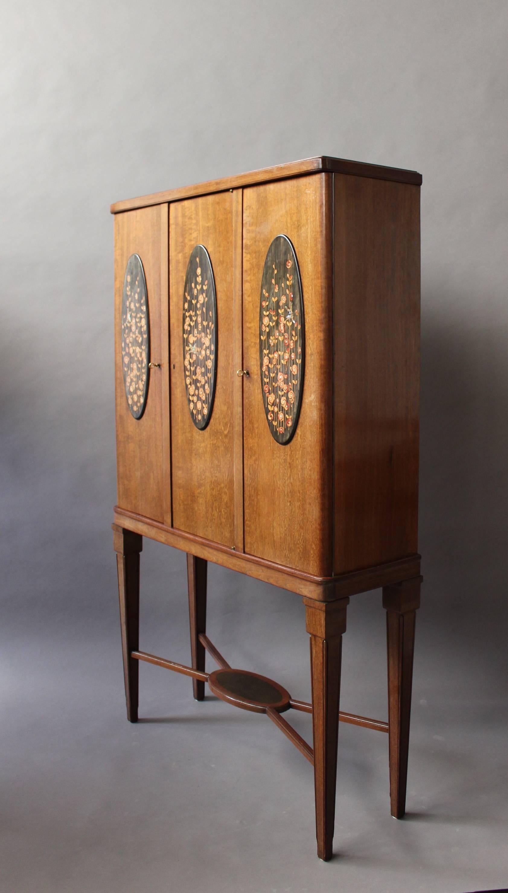 A fine French Art Deco three doors amaranth cabinet by Maurice Dufrene.
Each door decorated with a floral marquetry oval panel.
Interior is bird's-eye maple veneered.