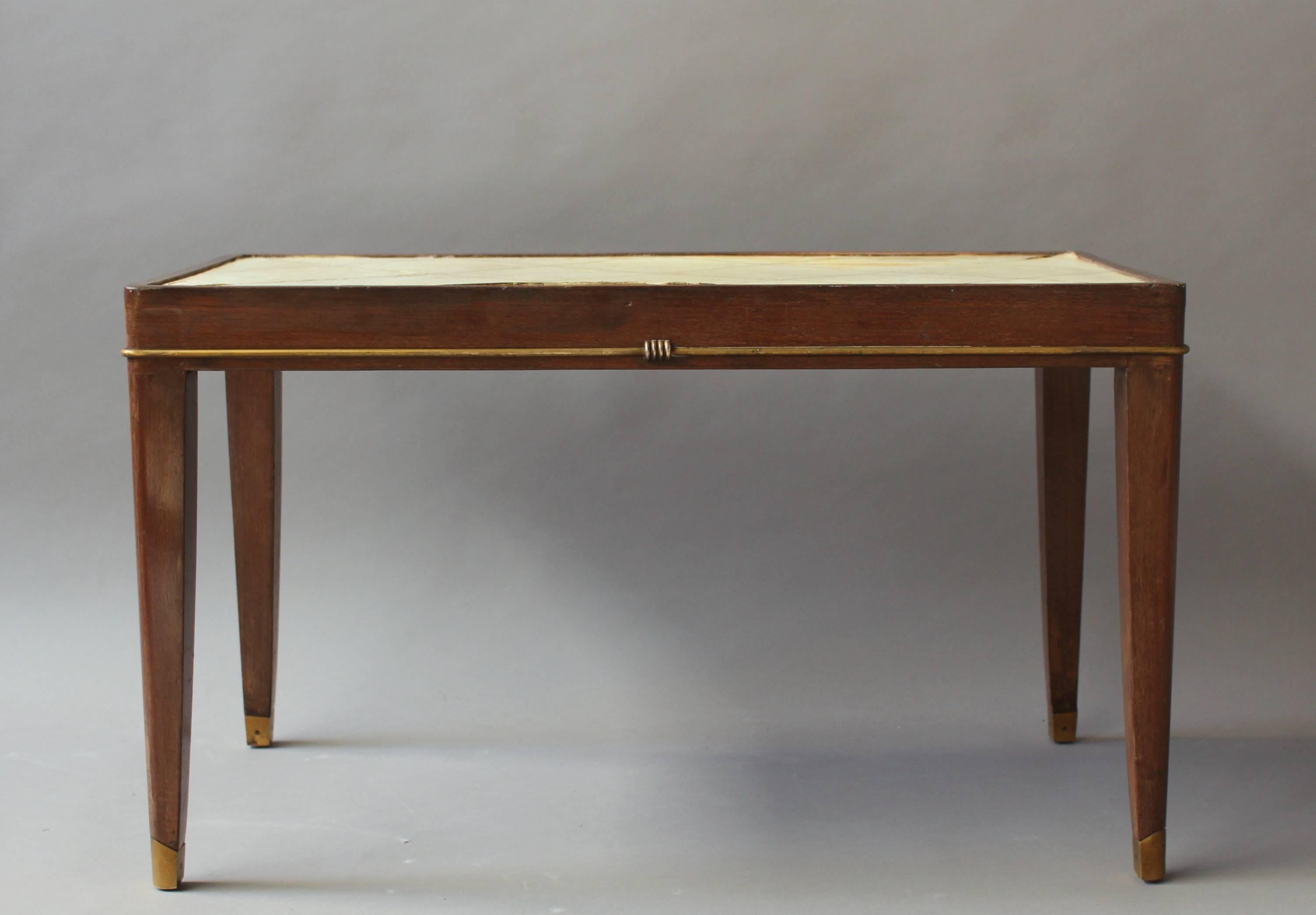 A fine French Art Deco mahogany coffee table with a parchment covered top and bronze details.