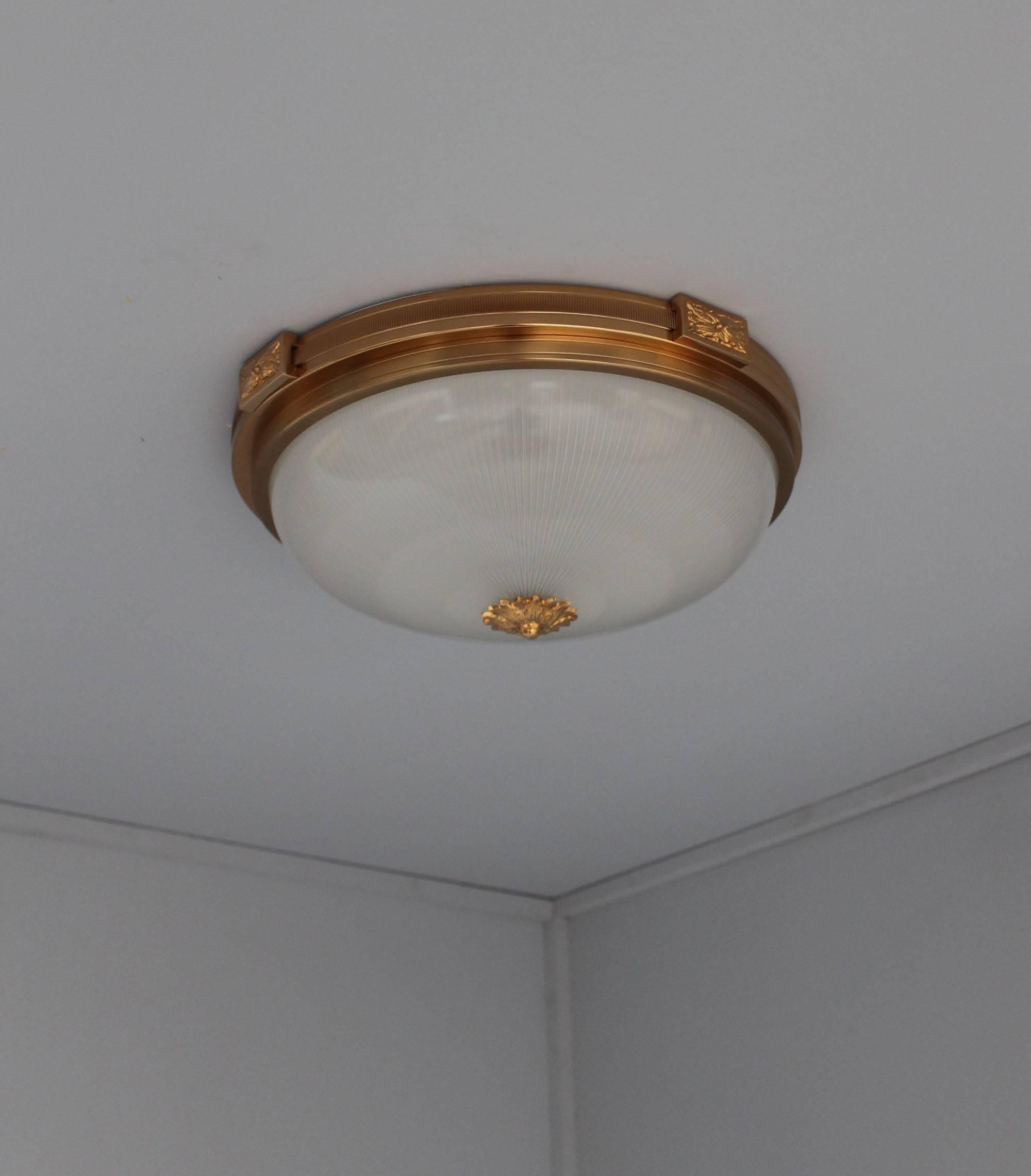 Three French neoclassical gilded lacquered brass flush mounts with a fluted glass diffuser.

Price is per piece and includes US re-wiring.