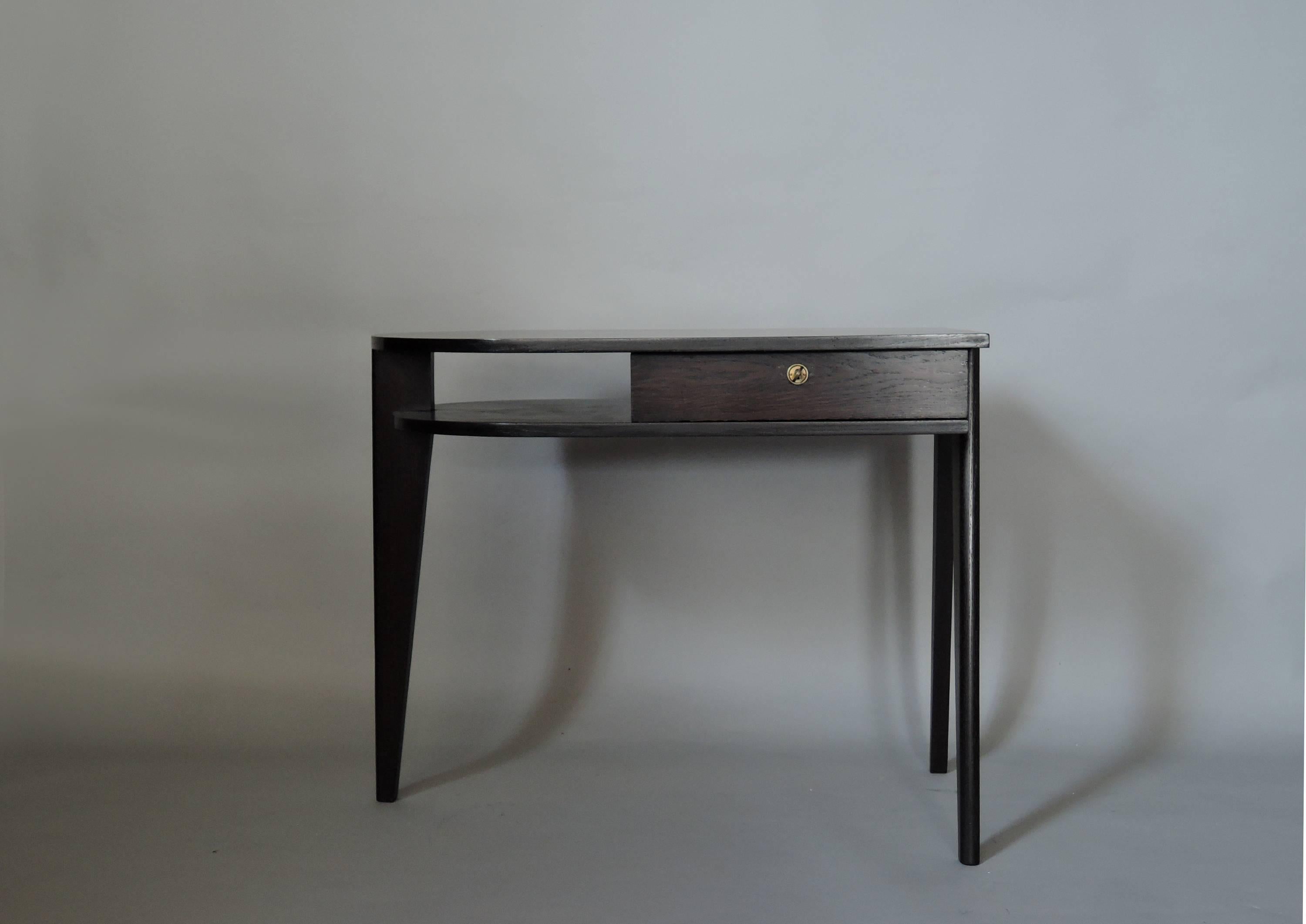 A fine French Mid-Century ebonized oak desk with three compass legs and one drawer with its original key.
 