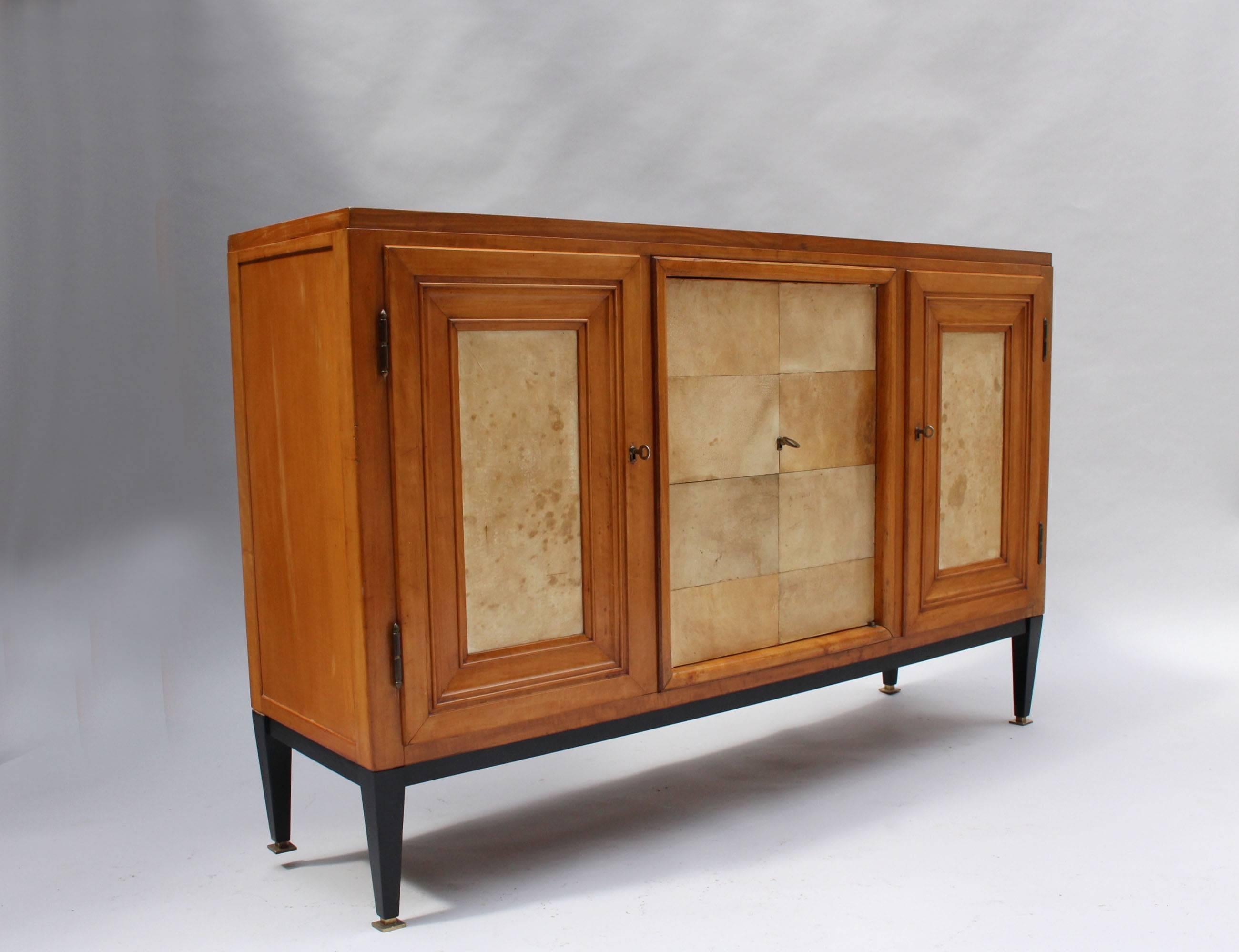 Sideboard with three parchment-covered doors, a pear wood case, blackened base and bronze details.
Stamped: Venus Mobel 1949.