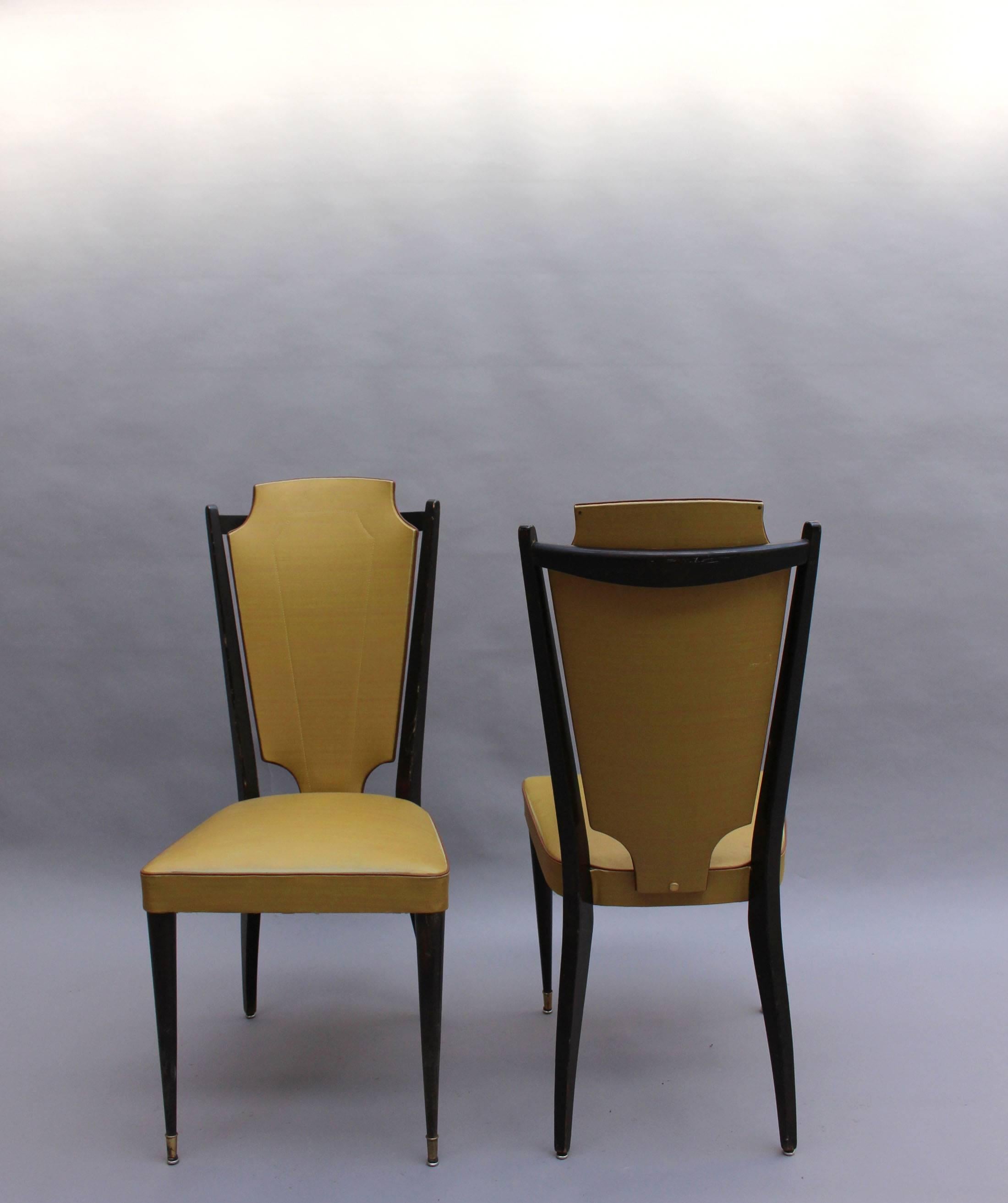 Ensemble de six chaises de salle à manger françaises des années 1960 en bois laqué noir et vinyle moutarde avec sabots en laiton.