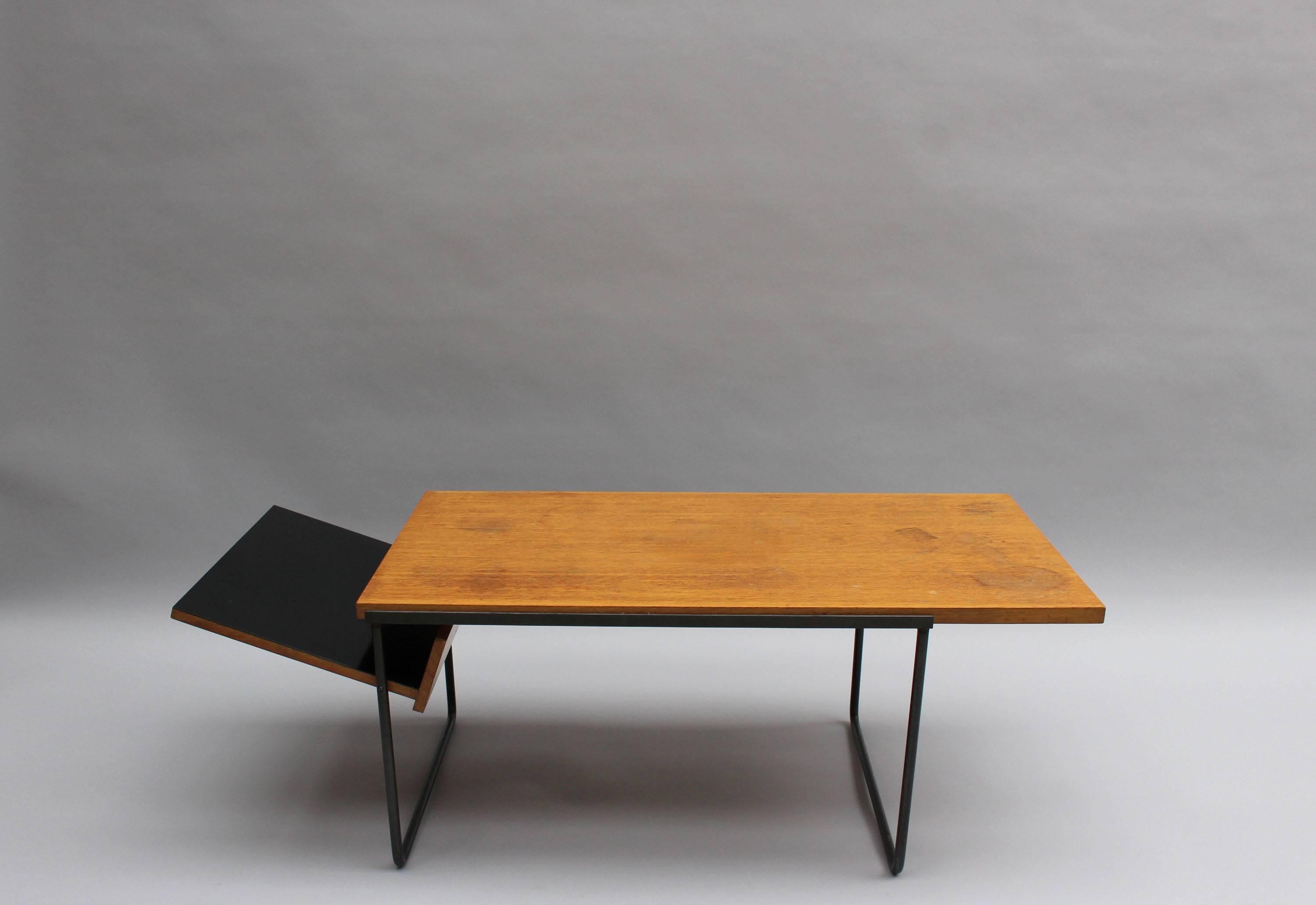 A fine French 1950's coffee table with a black lacquered metal base, an oak top and a black laminated magazine holder.