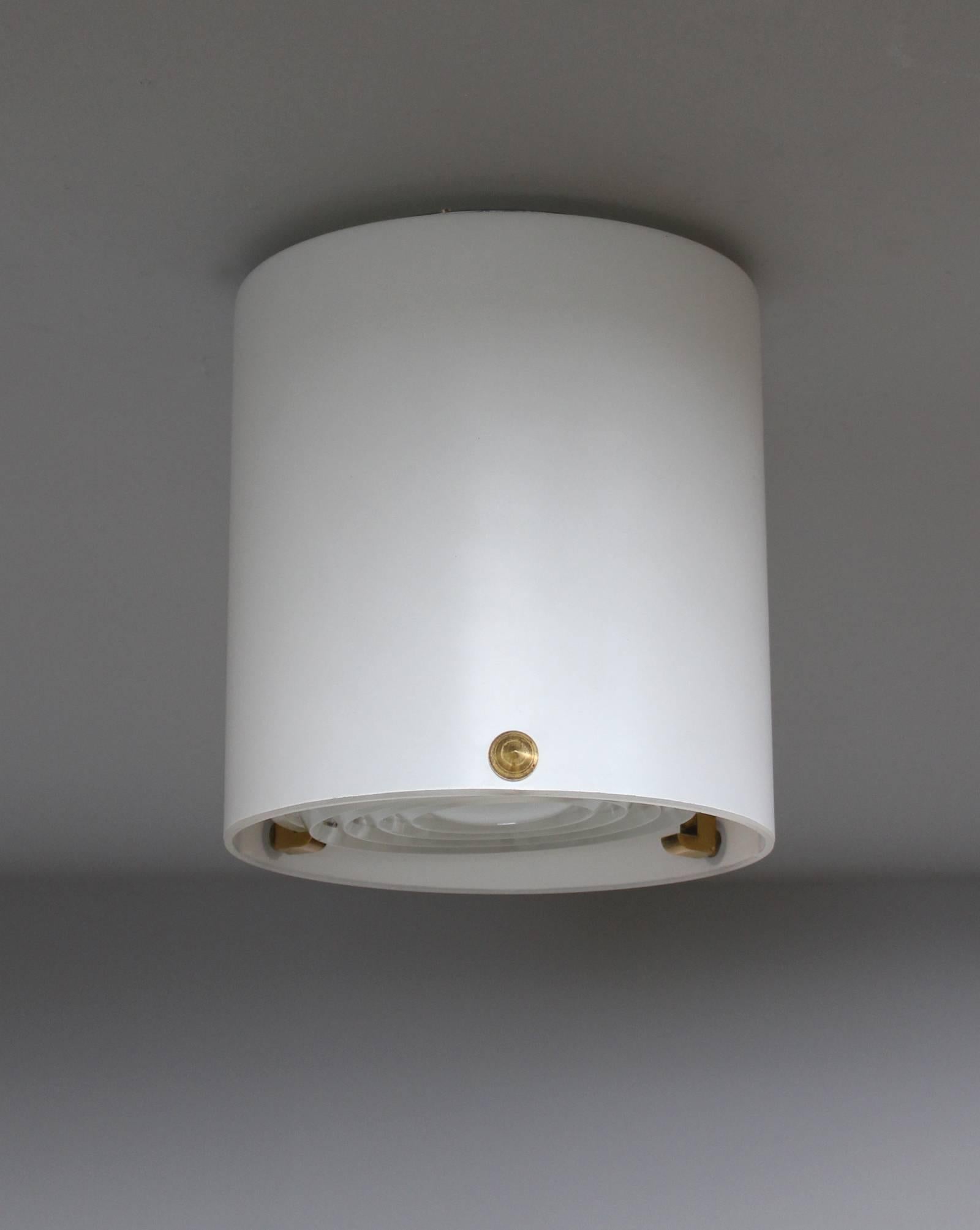 Two French 1950s cylinder-shaped flush mount or ceiling light in acid satin enameled glass by Jean Perzel with brass studs that support a prismatic frosted glass lens.
Price is per piece.